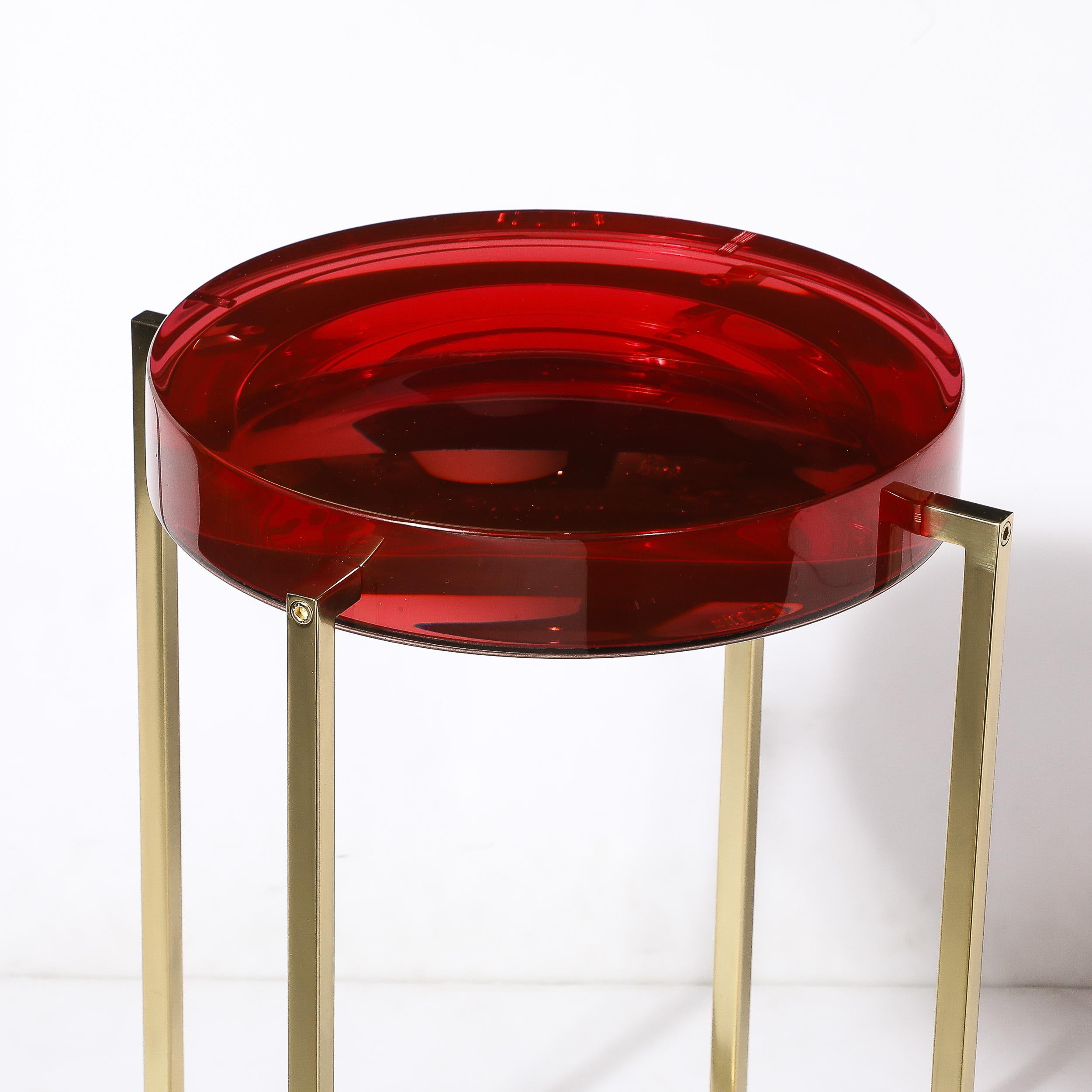 This playful and sleek Modernist Lens Side Table in Ruby Lucite and Brass is by McCollin Bryan and originates from England during the latter half of the 20th Century. Features a rectilinear brass framework that intersects in the center beneath the