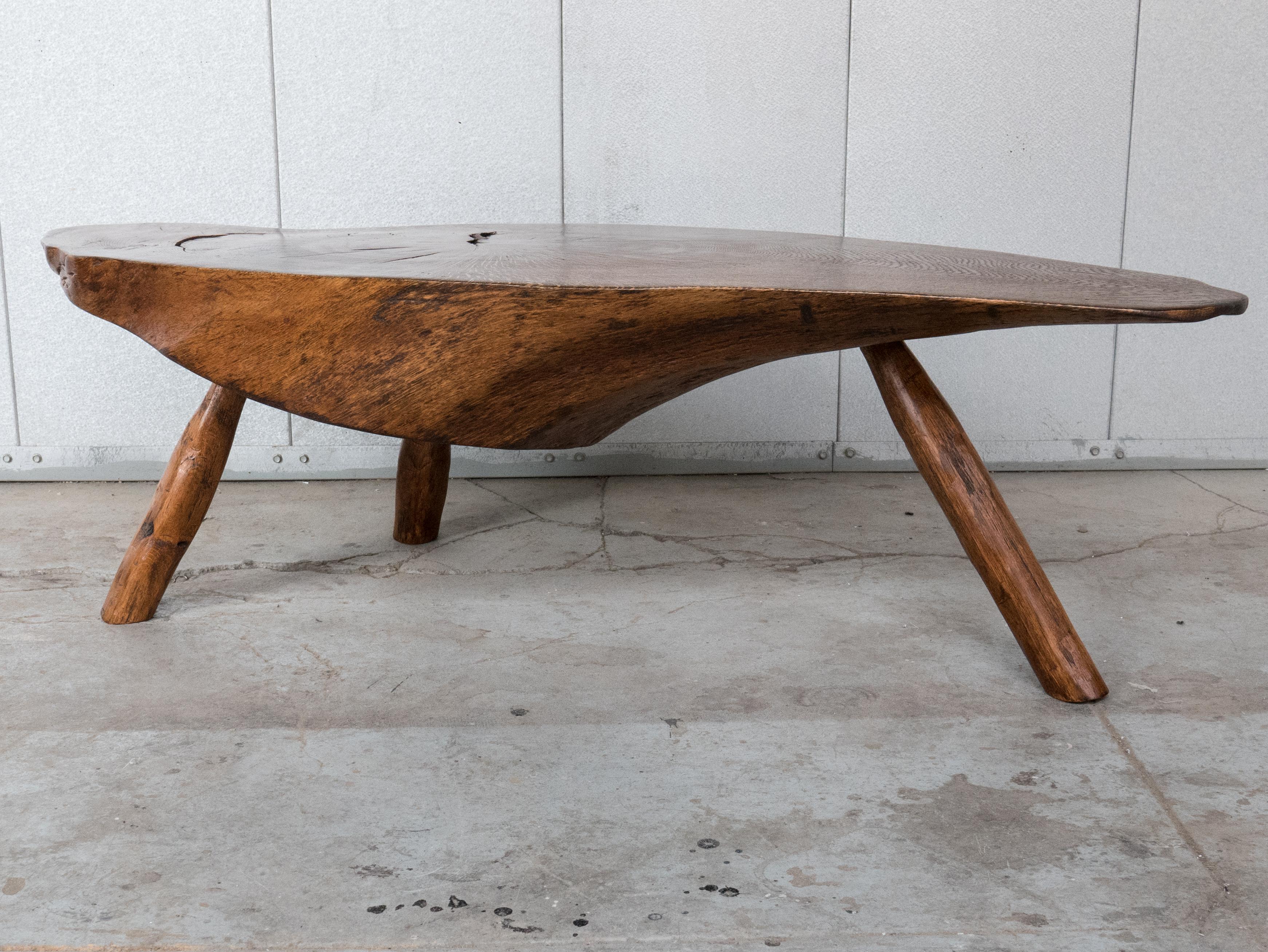 Live-edge cocktail table, made in Mexico, circa 1960s. The top is a cross-section of a nicely-grained guanacaste wood log; the whole is a modernist take on a vernacular design. Refinished.