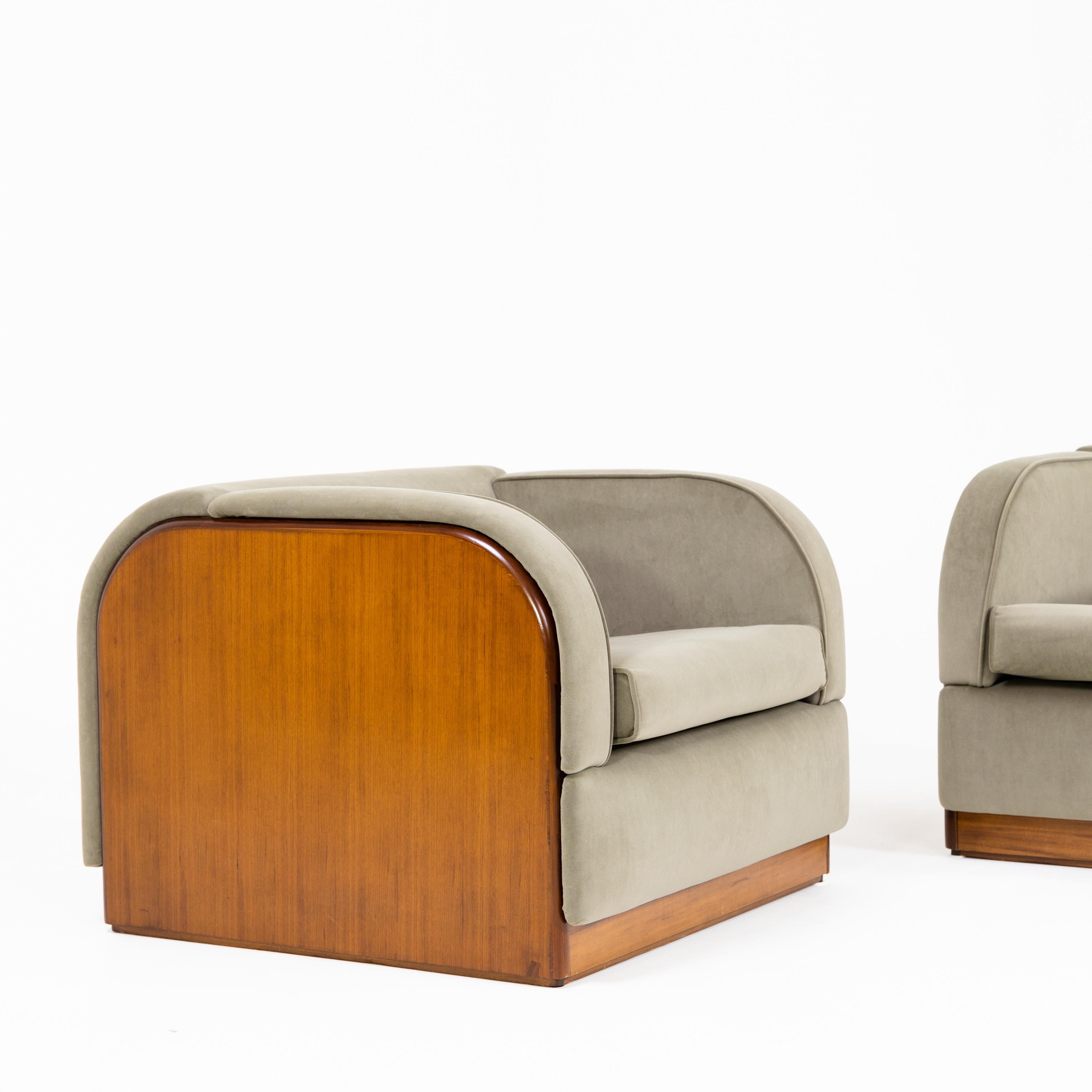Pair of lounge armchairs in cubic form with upholstered seats, arm and back rests. The veneered side panels are rounded, and the back is also upholstered and reupholstered in a green velvety fabric.