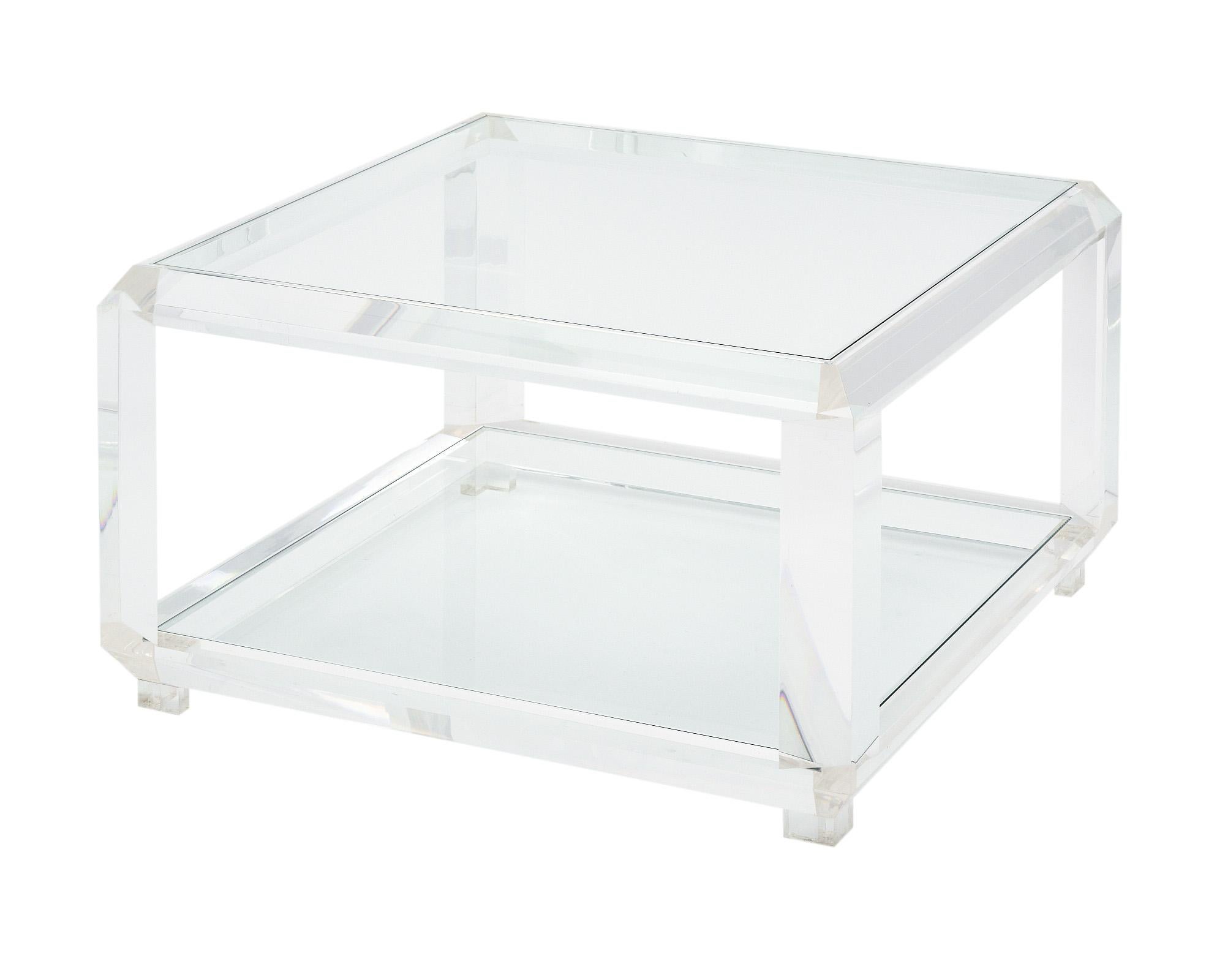 Pair of coffee tables from France made with thick Lucite structures and glass tops. Each table also features a lower glass shelf for functionality. They are each signed by designer Marc Micoud, known for working with Lucite.
