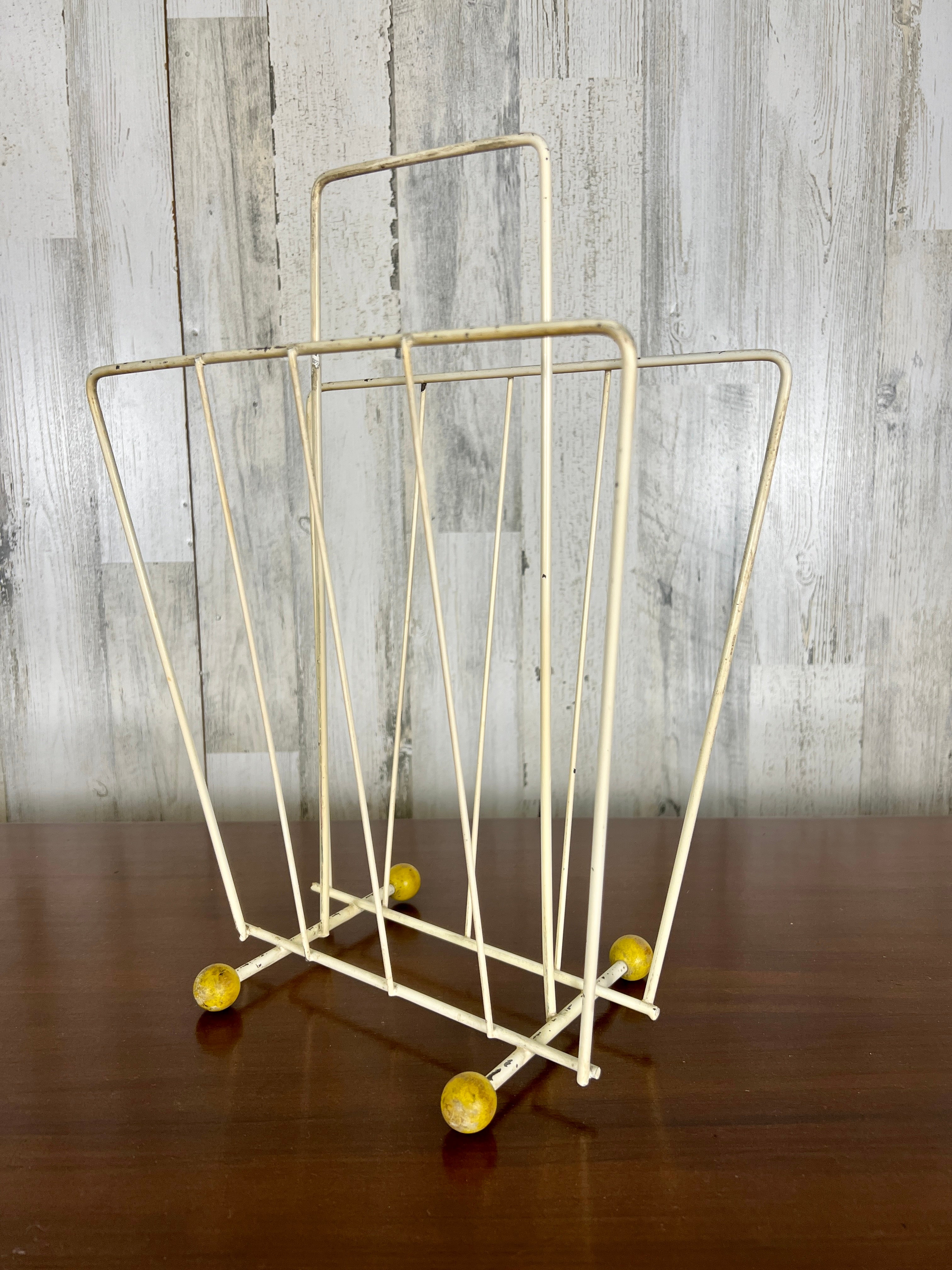 Modernist lacquered metal with wood ball feet magazine rack very space age.