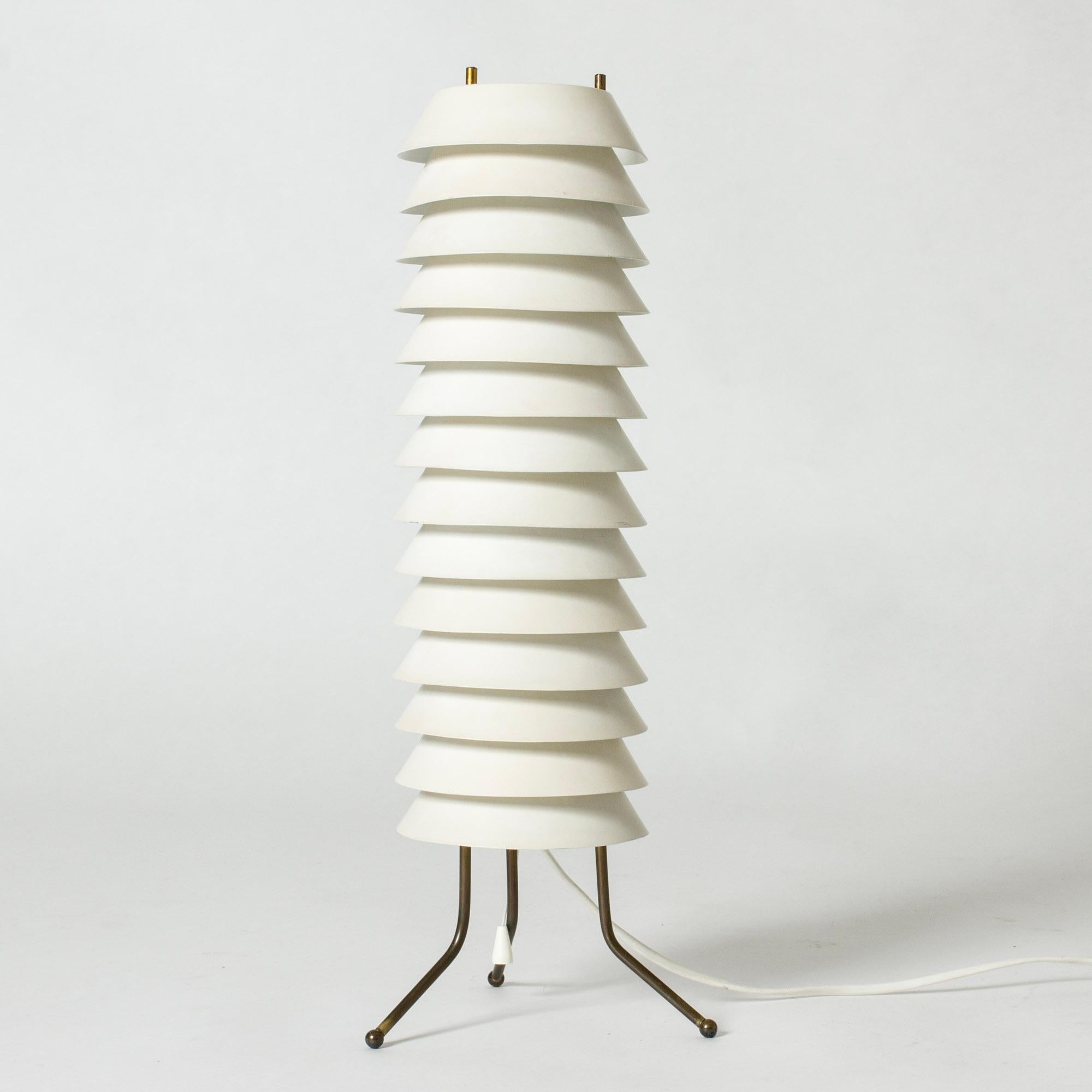 Striking “Maija Mehiläinen” (“Maija the Bee”) table lamp by Ilmari Tapiovaara. Stacked white lacquered lamellas in a tall cylinder form let out a soft light.