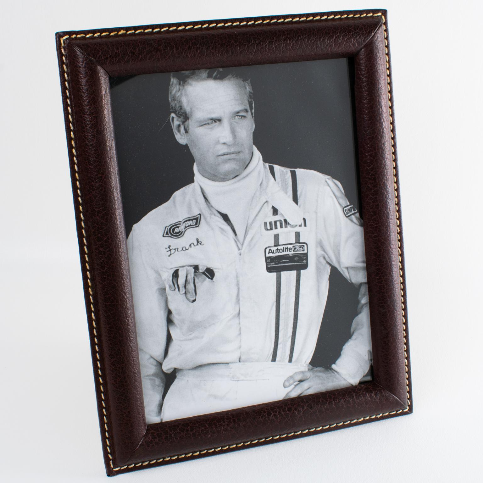 This luxury modernist leather picture frame was crafted in France circa 1950. The piece boasts fine-grain leather in a warm maroon color with white hand-stitched finishing. The easel and back are made of beige suede paper with a textured pattern,