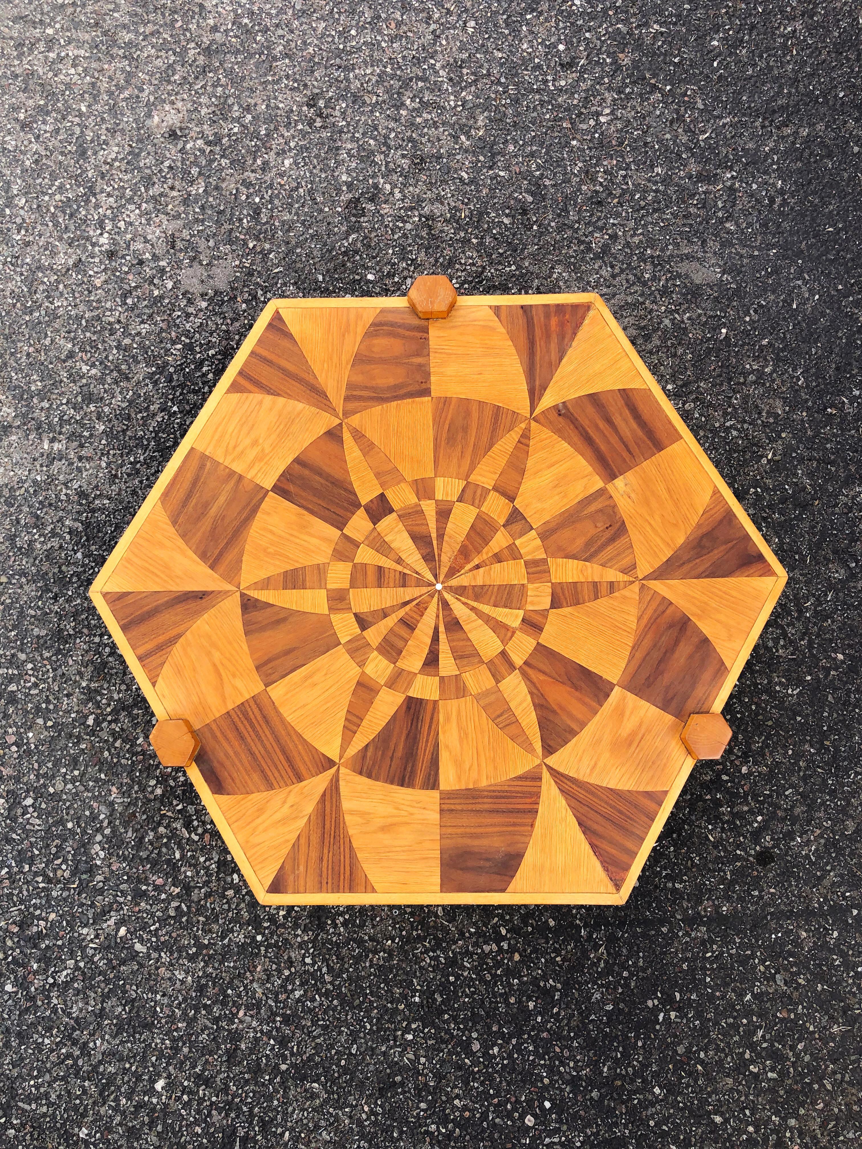 Vintage hexagonal inlaid wooden coffee table. Elaborate and stunning spiral marquetry inlay technique, featuring various shades of warm oaky wood and contrasting deep shades of brown. The geometric tabletop sits atop a modern 3 post frame, likely