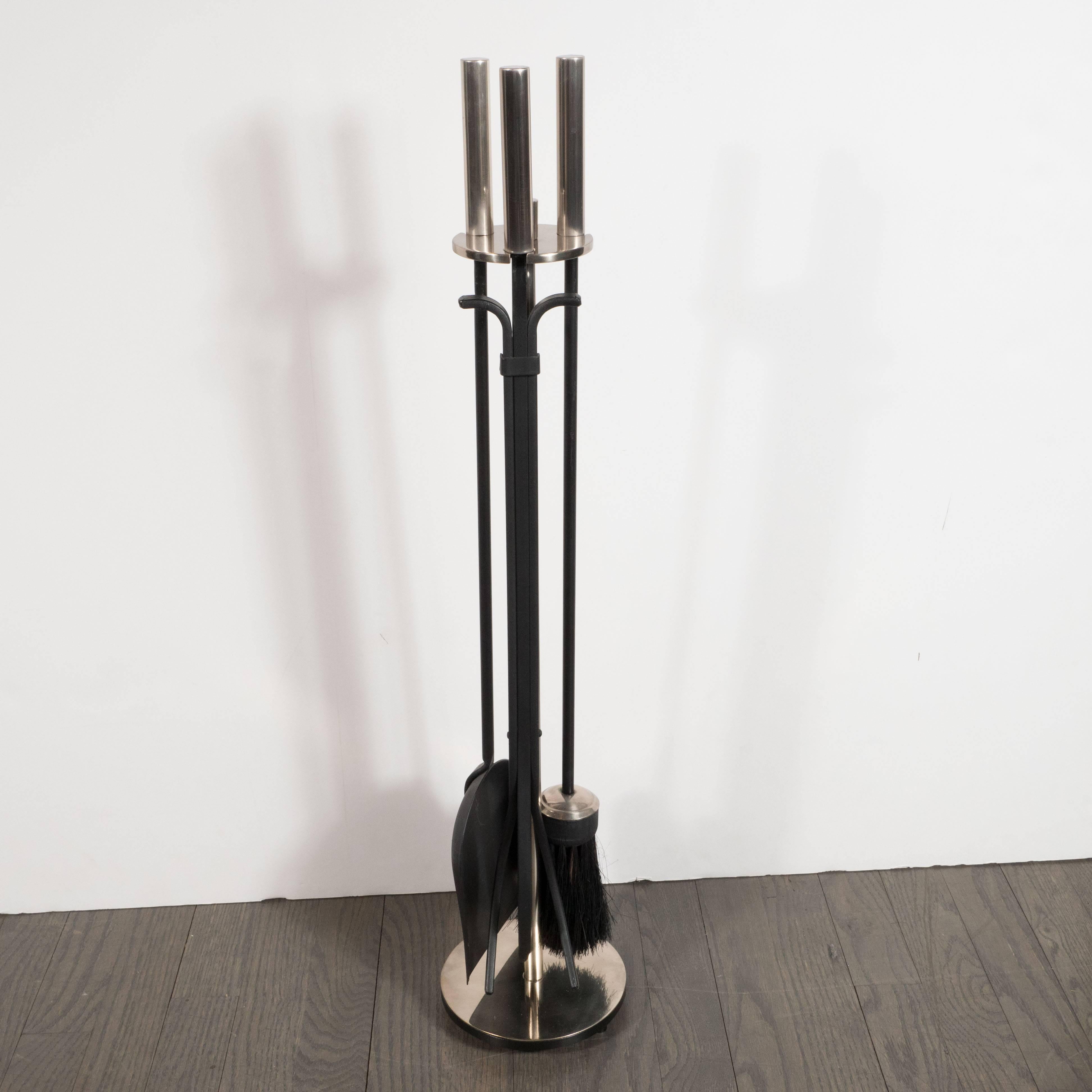 This handsome modernist four-piece fire tools set was realized by the renowned New York based fireplace tool company William H. Jackson, founded in 1827. Secured by a matte nickel stand with a cylindrical rod ascending from a circular base, it
