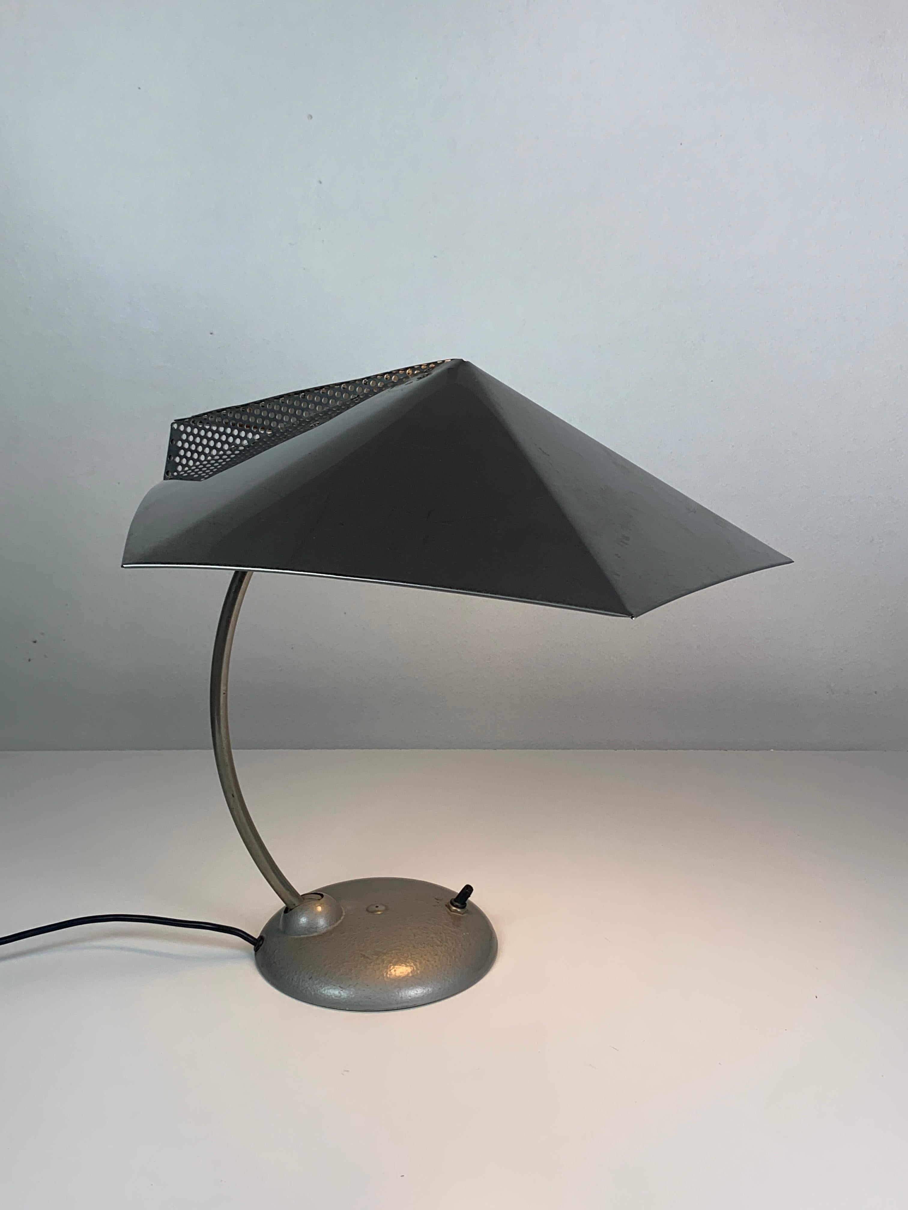 Une lampe de bureau absolument rare et inhabituelle avec un abat-jour perforé, des rivets en métal. Il y a des restes d'un ancien tampon ou d'une lettre sur le corps de la lampe (voir photo) mais malheureusement illisible (si quelqu'un sait ce que