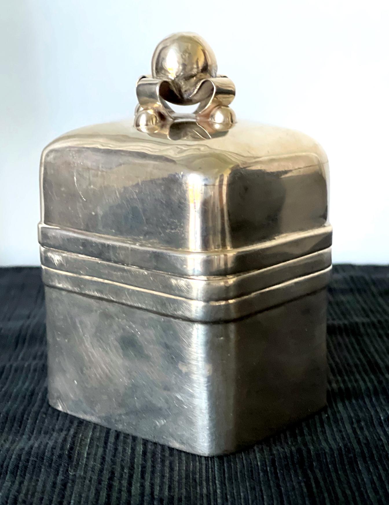 A lovely sterling silver caddy or table top box made in Taxco Mexico by William Spratling, circa 1944-1946. The box features a cube form with rounded corner with three stylized matching bands in the midbody where the lid close. The top knob has a