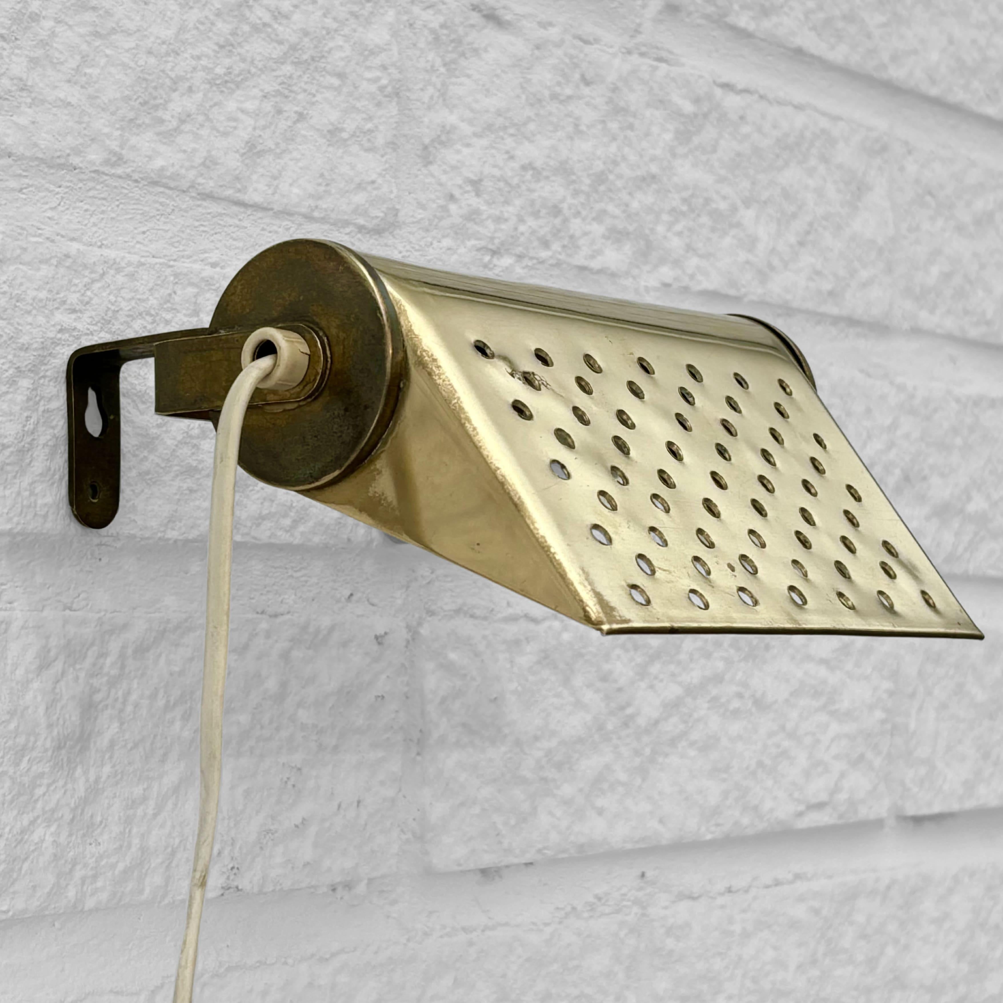 Una lampada da parete o da comodino modernista, realizzata in ottone massiccio con un paralume inclinabile perforato da un motivo geometrico di fori. Può essere montato direttamente sulla parete o su una testata del letto utilizzando le due viti
