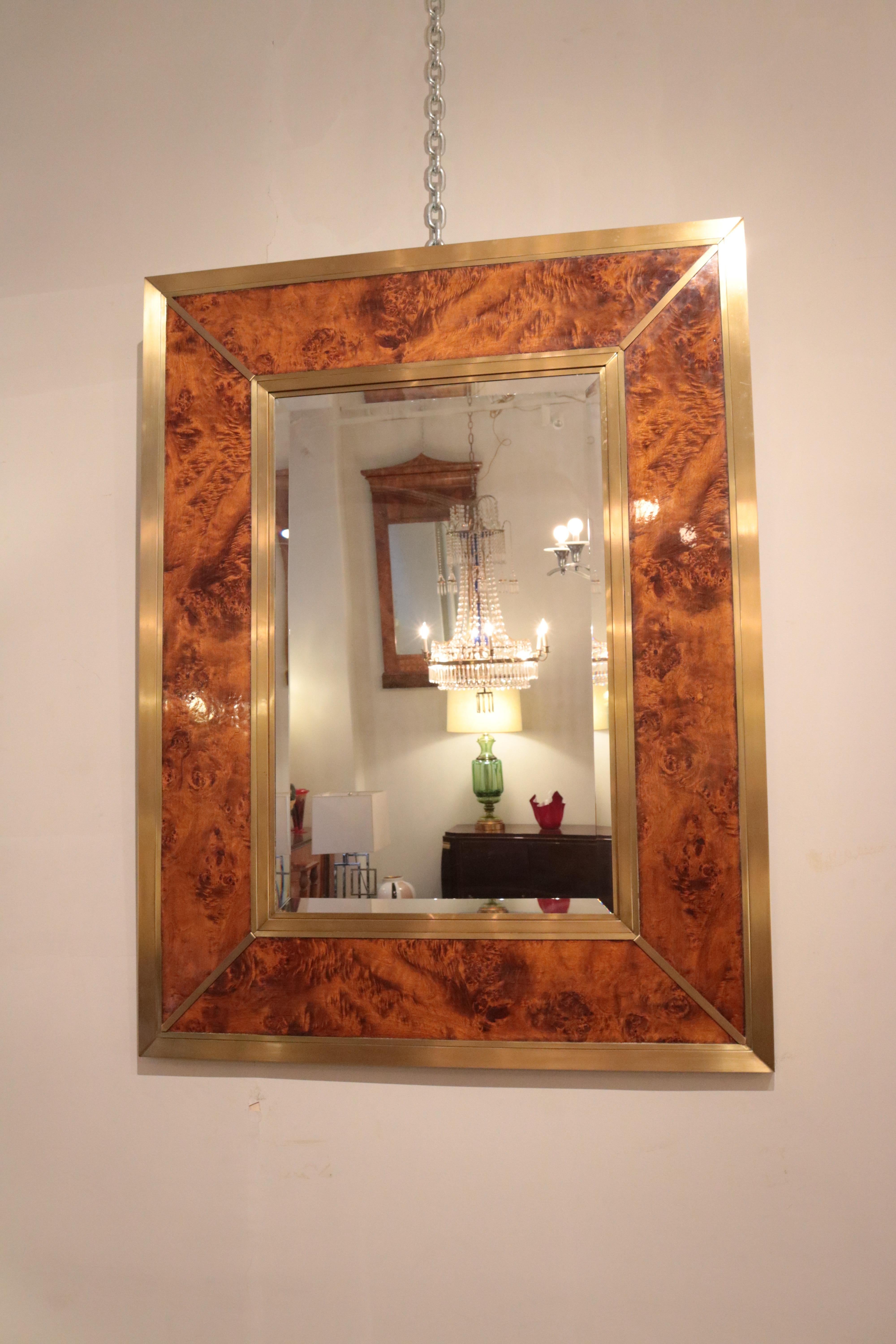 A modernist mirror crafted of walnut burl
and patinated brass with central beveled mirror.