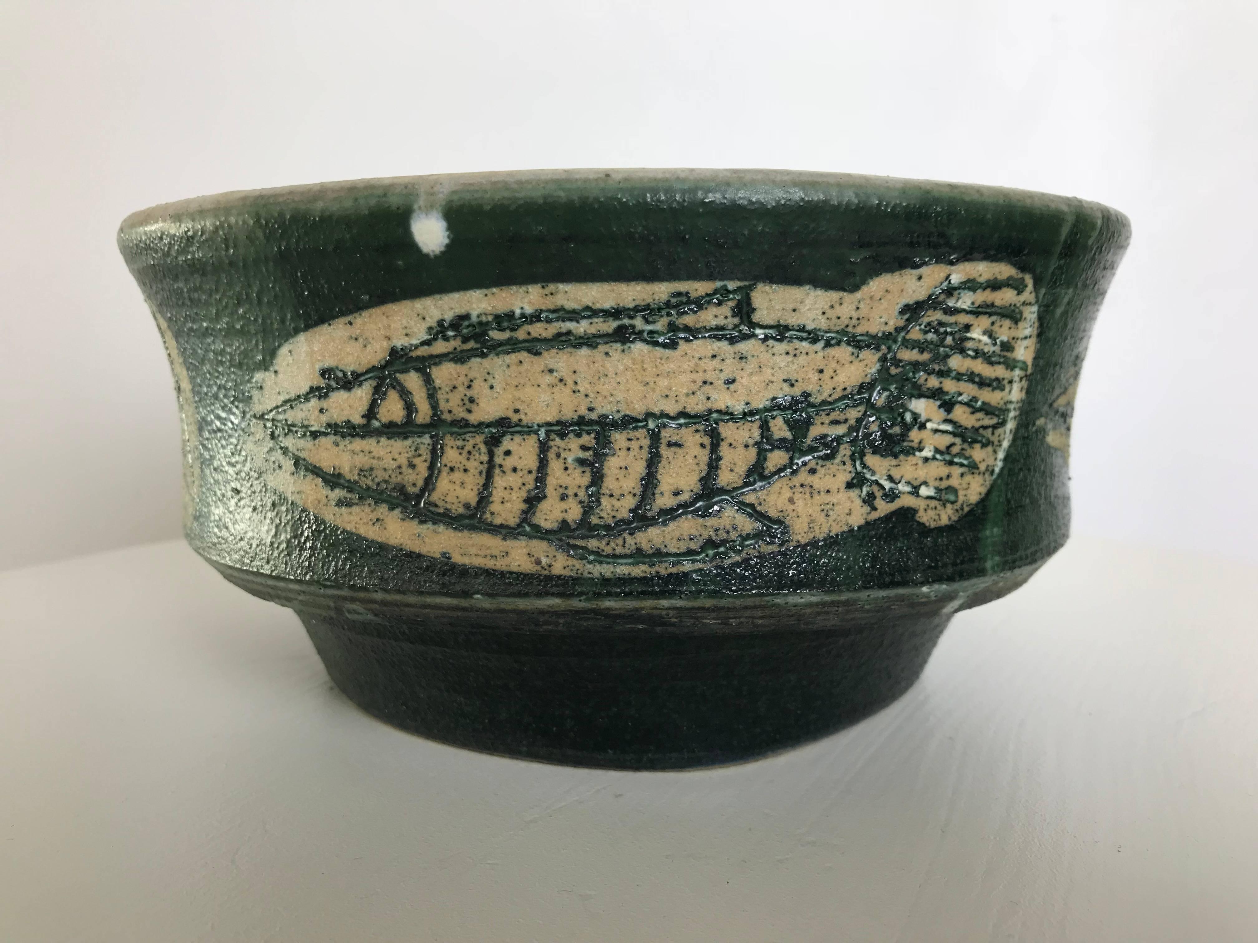 Wonderful footed hand-thrown bowl by listed Florida artist/sculptor/potter Frank Colson, featuring a Neolithic fish pattern. This bowl is in excellent condition with no issues to report. The glaze and color are as rich as they were when it was made.