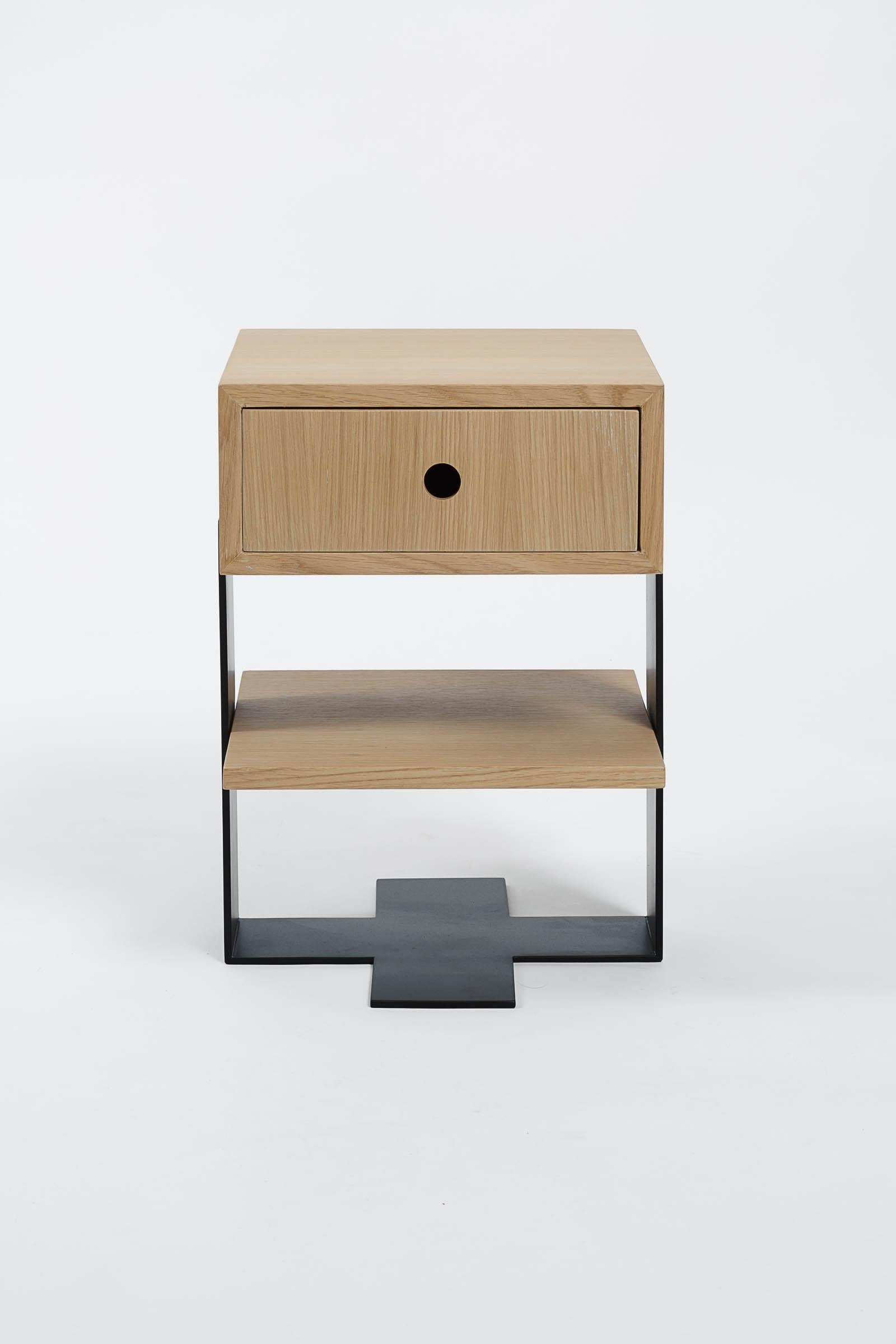 The Mayet bedside table consists of a drawer veneered in oak, levitating on a mat black steel base, hand polished and welded. A shelf also hand veneered in oak nests below the drawer for additional storage space. This designer bedside table, which