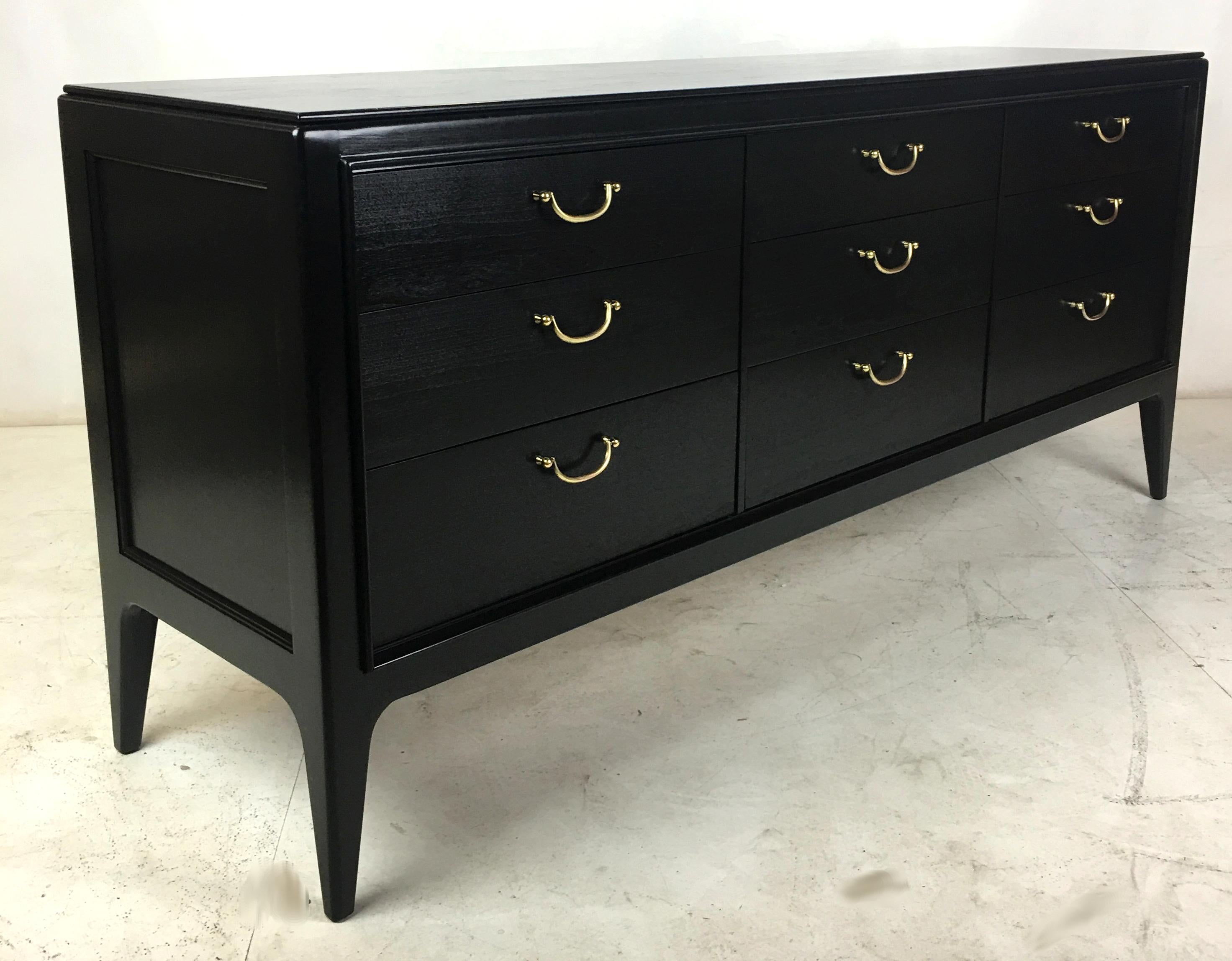 Handsome Neoclassical Modern nine-drawer dresser with tapered legs and brass bail pulls. The piece has been restored from the ground up and refinished in Ebony lacquer. The pulls were hand polished preserving just enough of their vintage patina.