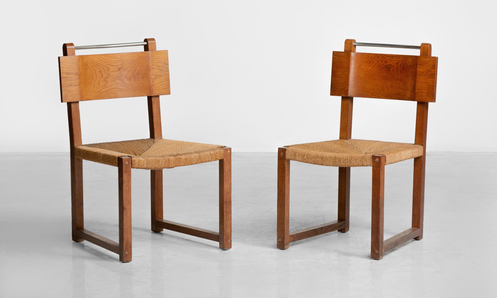 Modernist oak and rush side chairs, Czechoslovakia, circa 1930.

Concave oak table back and polished steel bar above a danish cord seat.
Measures: 19.5