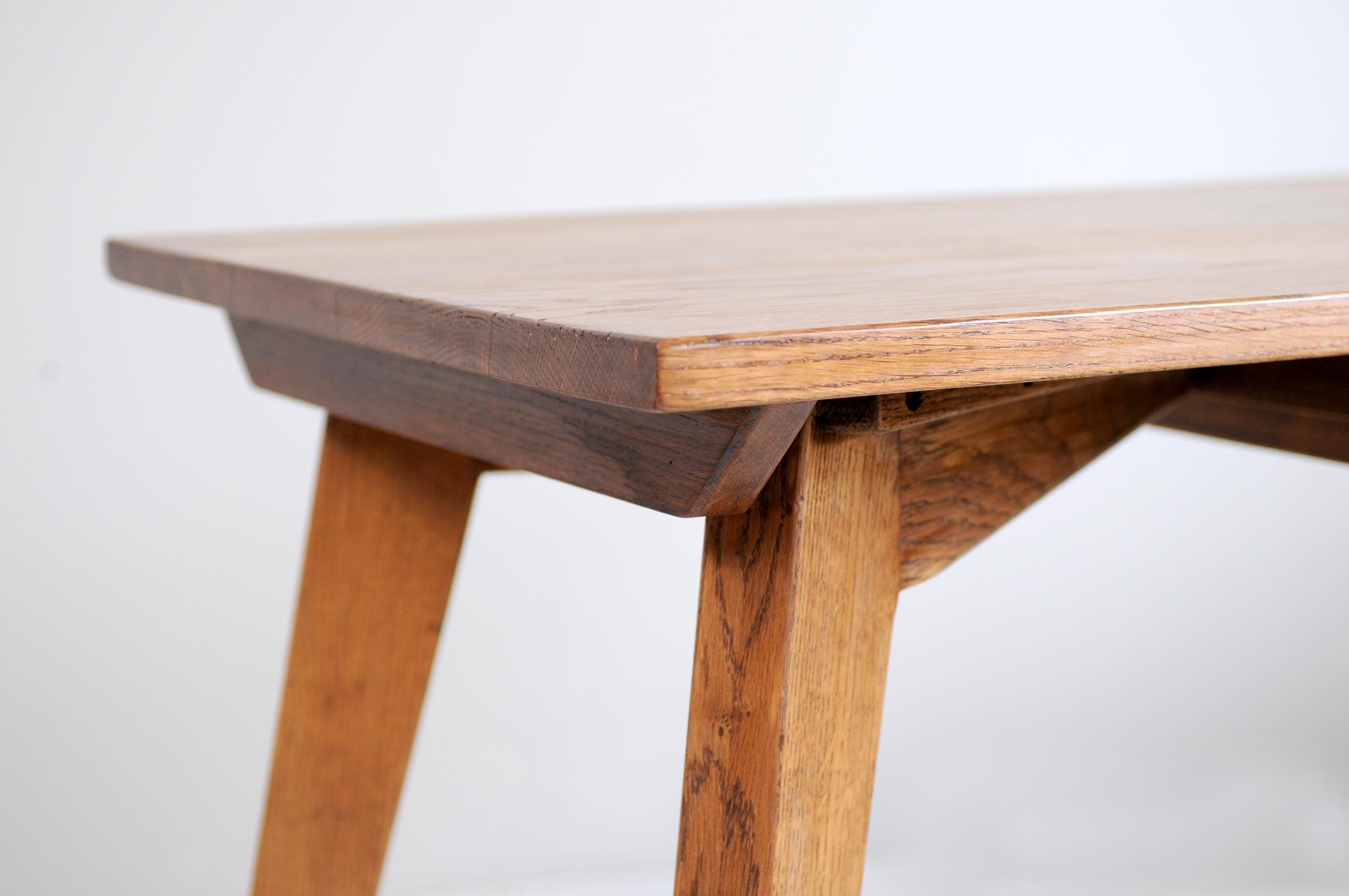 Table in solid oak, France 1950. The top, reinforced by four cross-sections, has a central drawer sliding freely on both sides.
The design of the base in the form of a compass, the use of blond oak, its gathered and dynamic line give this work of