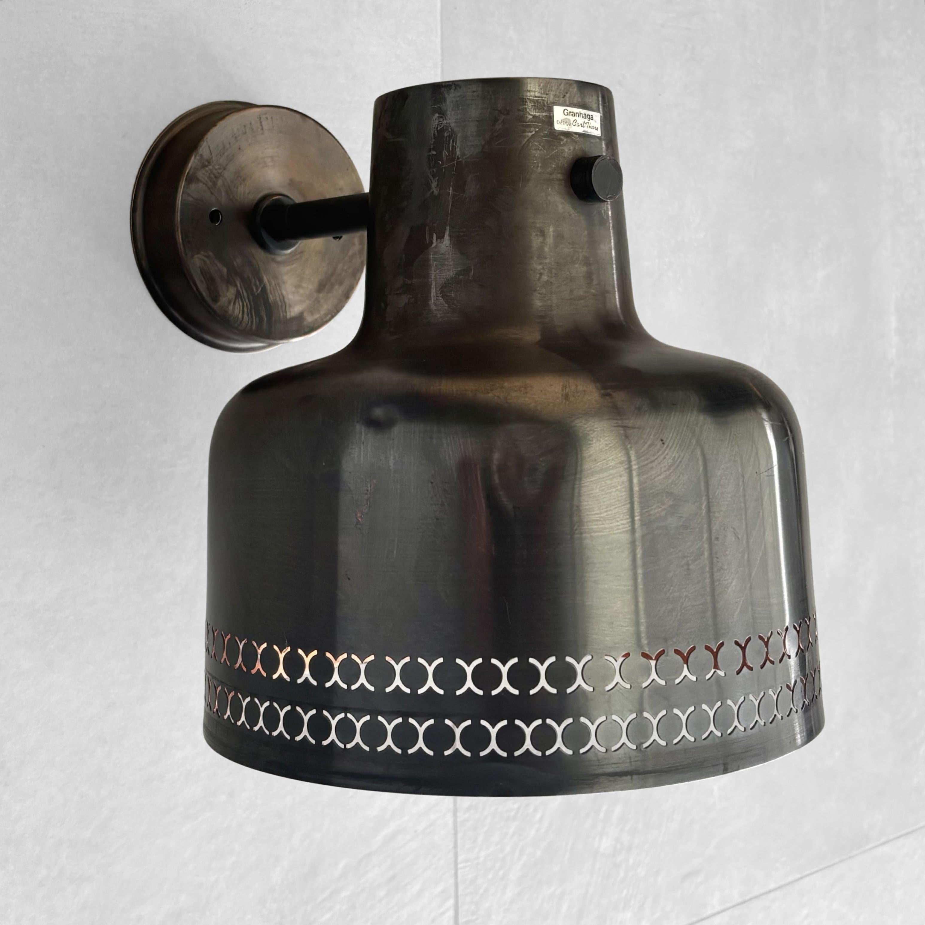 Une applique extérieure moderne du milieu du siècle, conçue dans les années 1960 par Carl Thore pour le fabricant suédois Granhaga Metallindustri. Fabriquée en cuivre avec un extérieur oxydé et un intérieur laqué, la lampe présente un motif