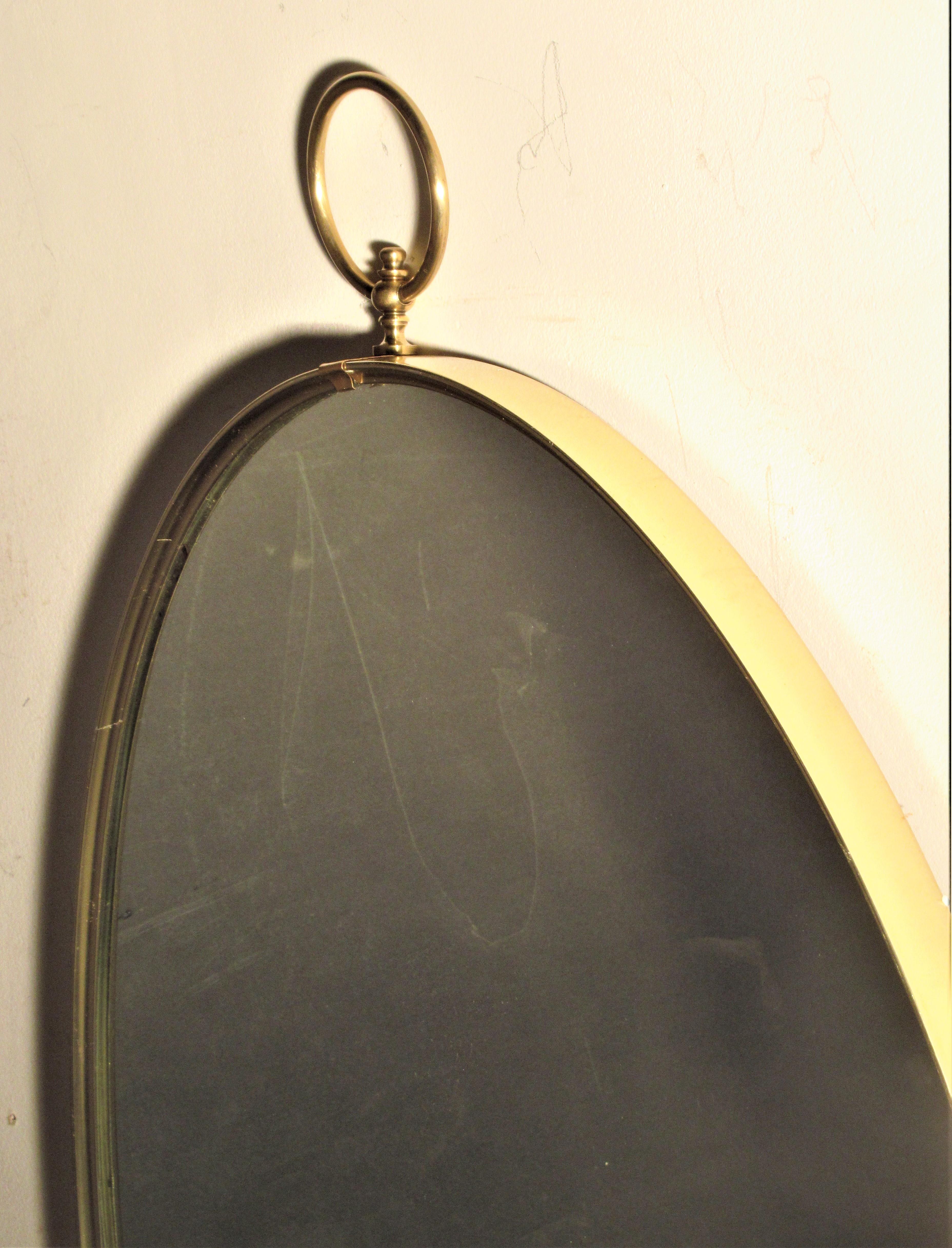 Oval brass mirror with large ring top center of frame. In the Italian modernist style of Gio Ponti, circa 1950-1960. Look at all pictures and read condition report in comment section.