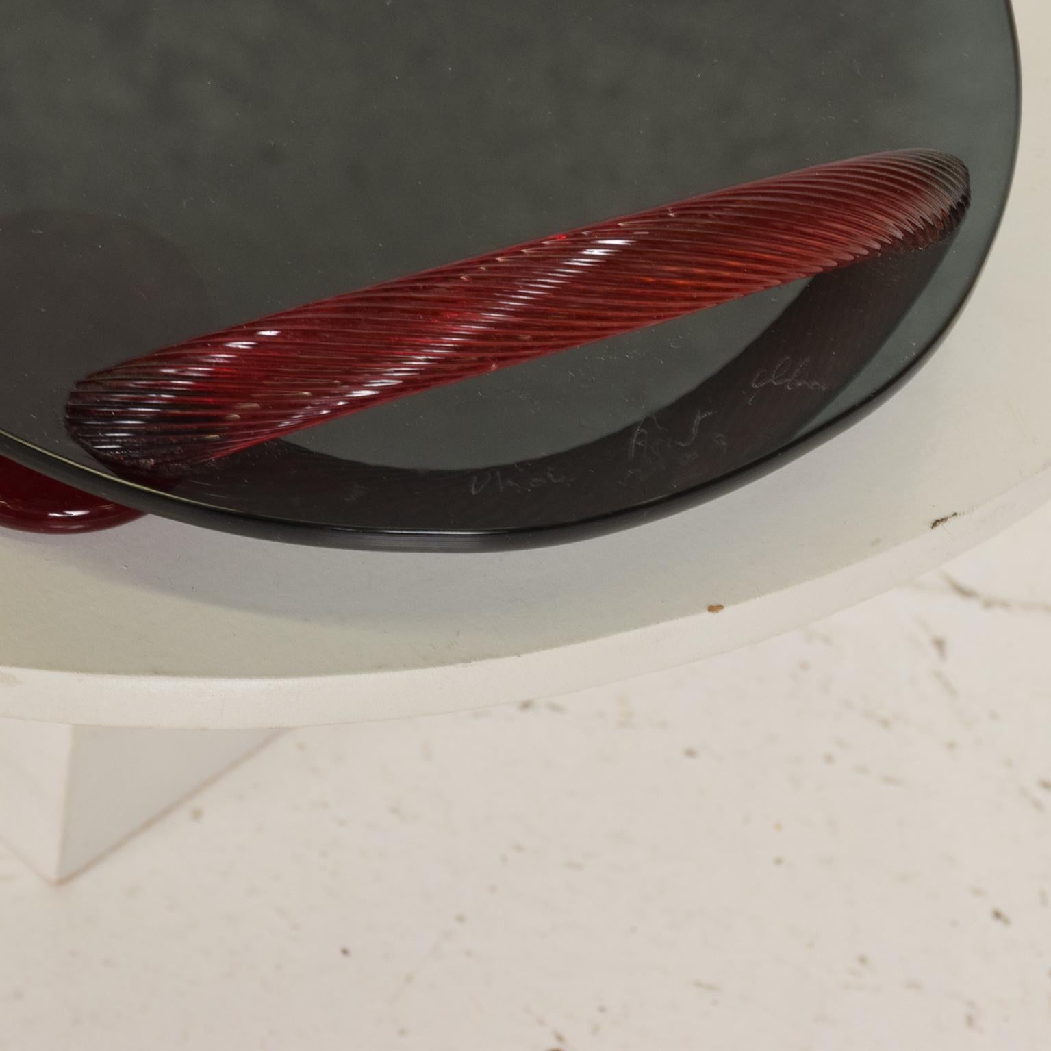 For your consideration, a modernist oval serving tray in smoke glass with red ruby glass handles and sabots. Signed on one side, unable to make up the signature from the maker.