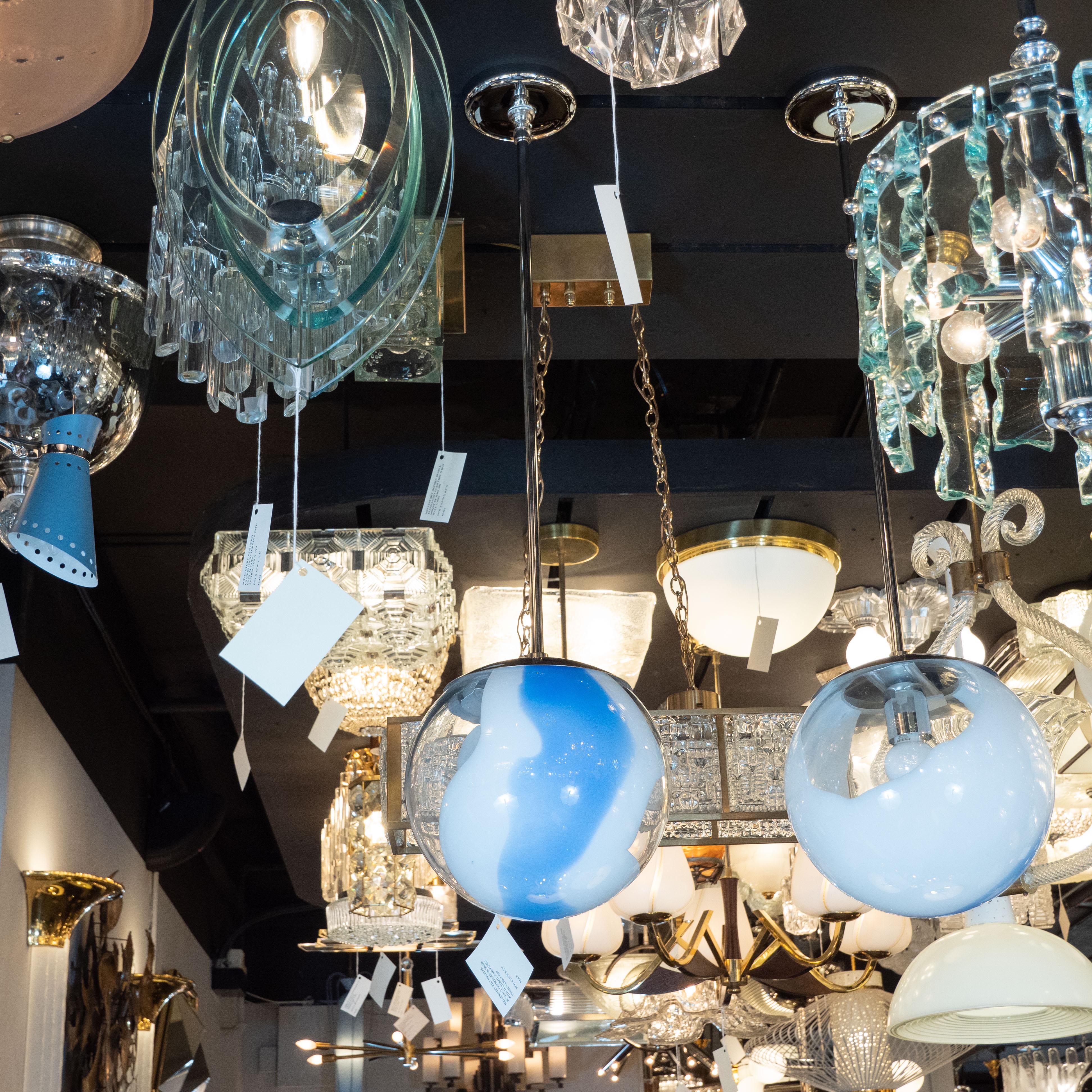 This stunning pair of modernist pendants were hand blown in Murano, Italy- the island off the coast of Venice renowned for centuries for its superlative glass production. They feature spherical forms realized in translucent glass with opaque white