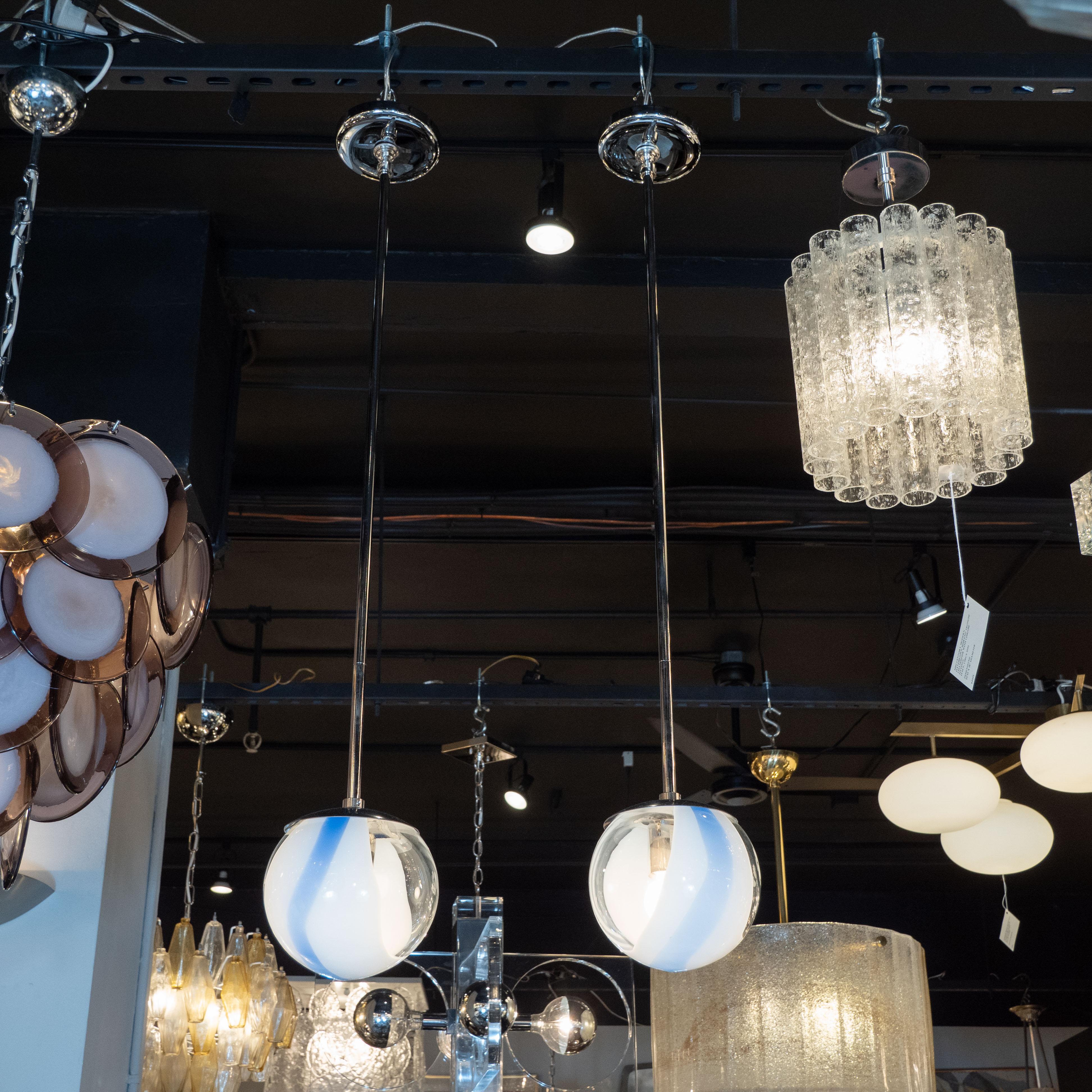 This stunning pair of modernist pendants were hand blown in Murano, Italy- the island off the coast of Venice renowned for centuries for its superlative glass production. They feature spherical forms realized in translucent glass with opaque white