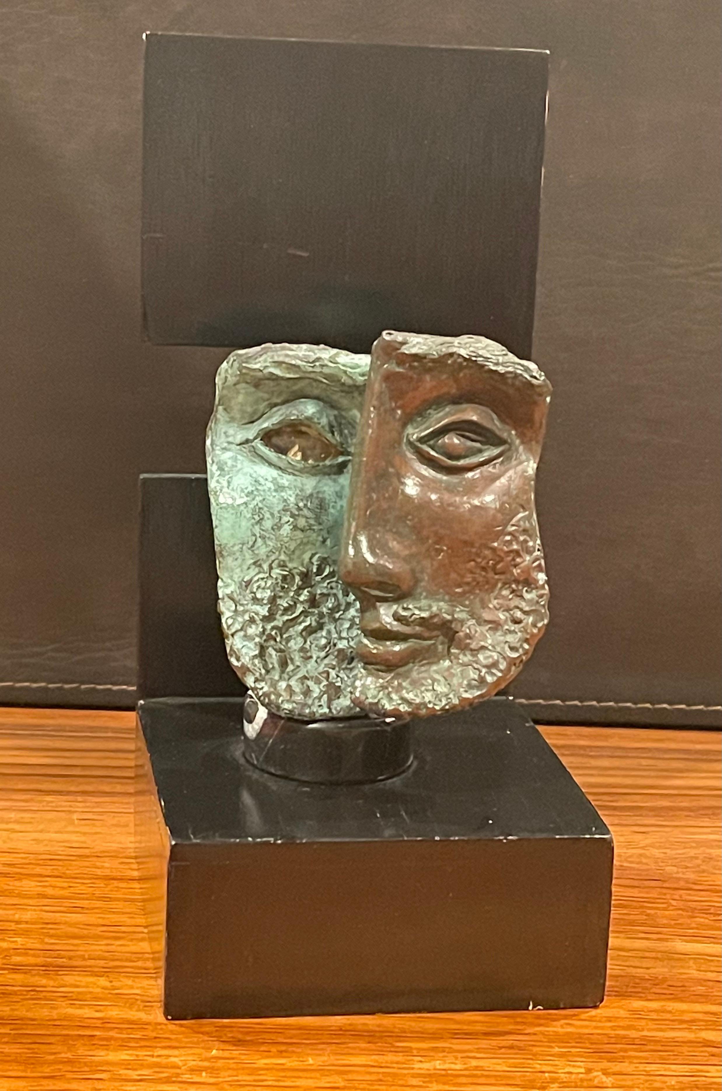 Modernist patinated bronze sculpture on a black wood base, circa 1960s. The piece has a 3-dimensional face (Julius Ceasar?) in bronze that is mounted to a small marble disk and the attached to a black wood base. The face is presented in two separate