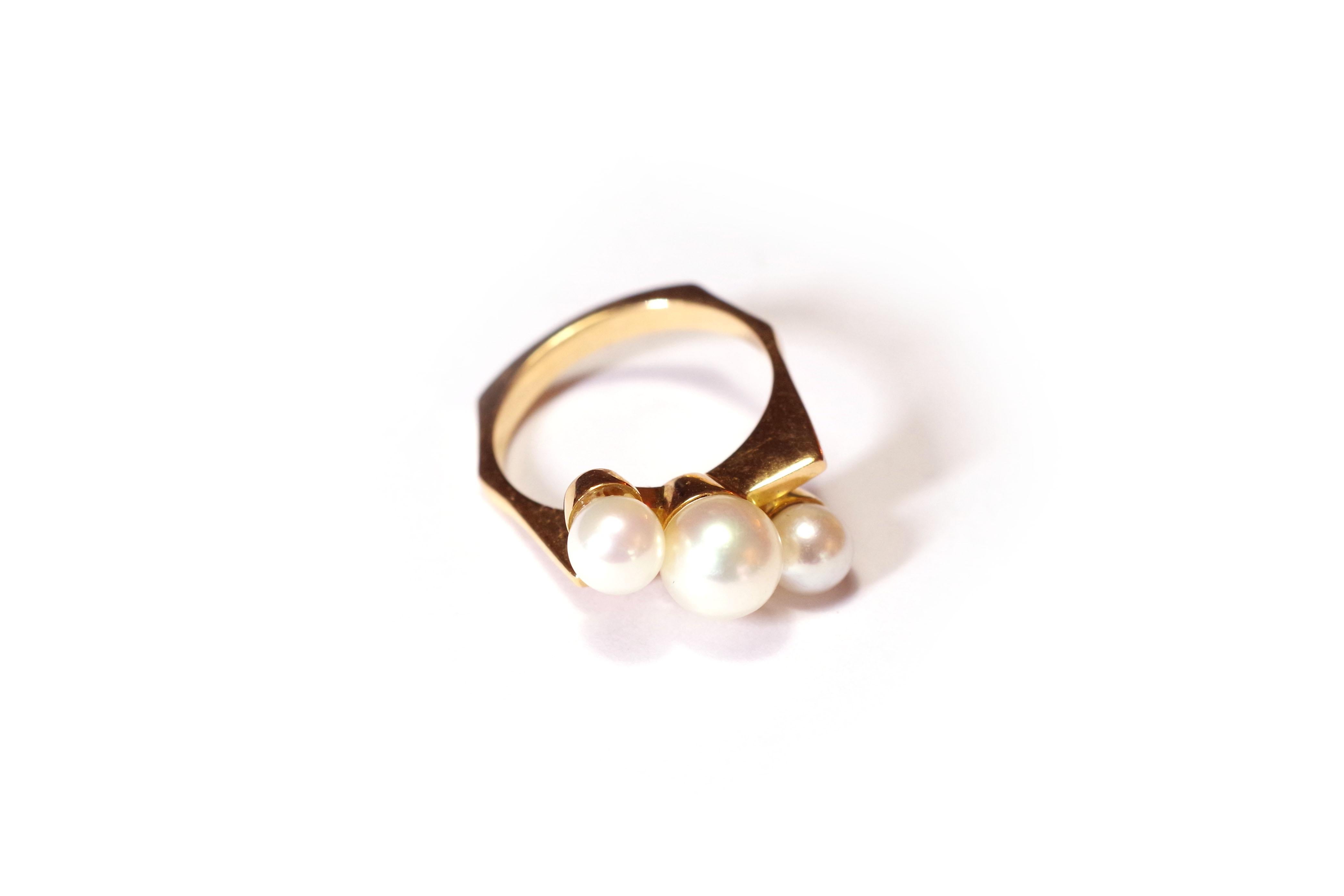 Modernist pearl ring in 18 karat yellow gold centred with three white cultured pearls forming a diagonal. The ring adopts a hexagonal shape. French ring of the second half of the 20th century.

Eagle's head hallmark and erased hallmark of the