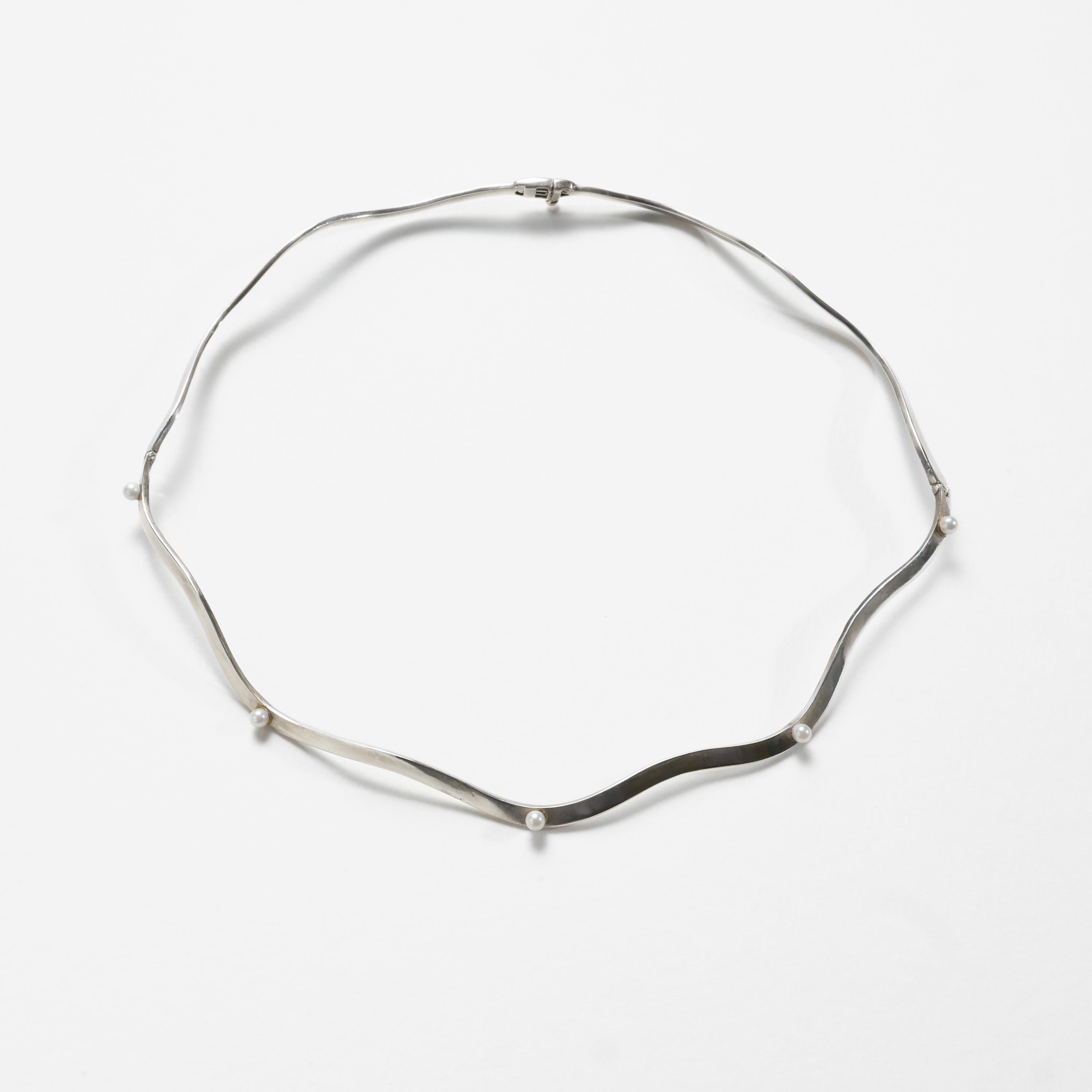 Dieses modernistische (ca. 1970er Jahre) und minimalistische, segmentierte Collier aus Perlen und Silber wurde so konzipiert, dass es nicht nur als Halskette, sondern auch als Brautdiadem getragen werden kann.

Die Halskette misst ca. 16,5