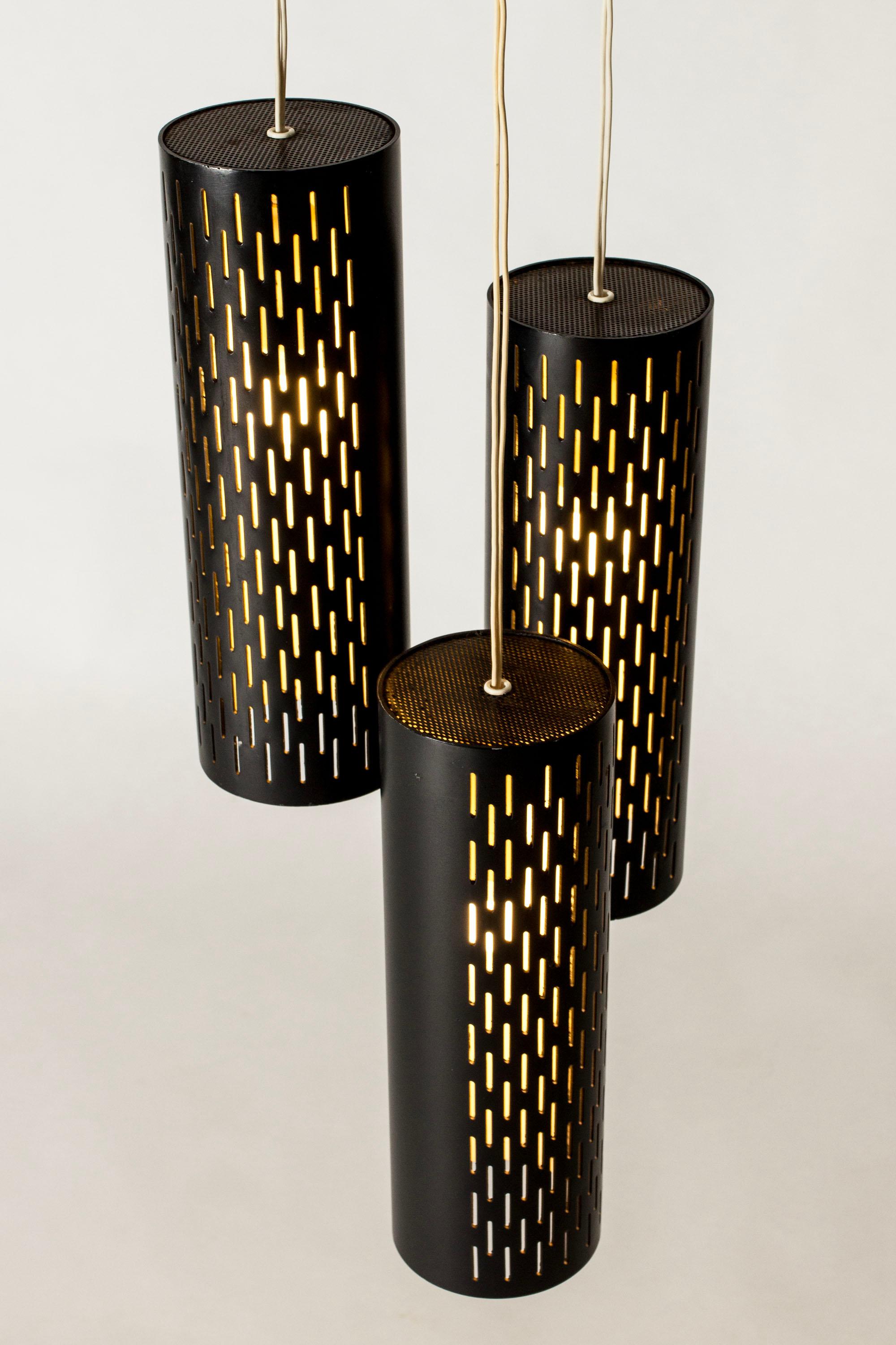 Raffinata lampada a sospensione di Hans Bergström, realizzata in metallo laccato nero. Tre cilindri sospesi a diverse altezze, perforati con un motivo grafico di fessure. Un elegante dettaglio in ottone separa le Corde.

Hans Bergström era il