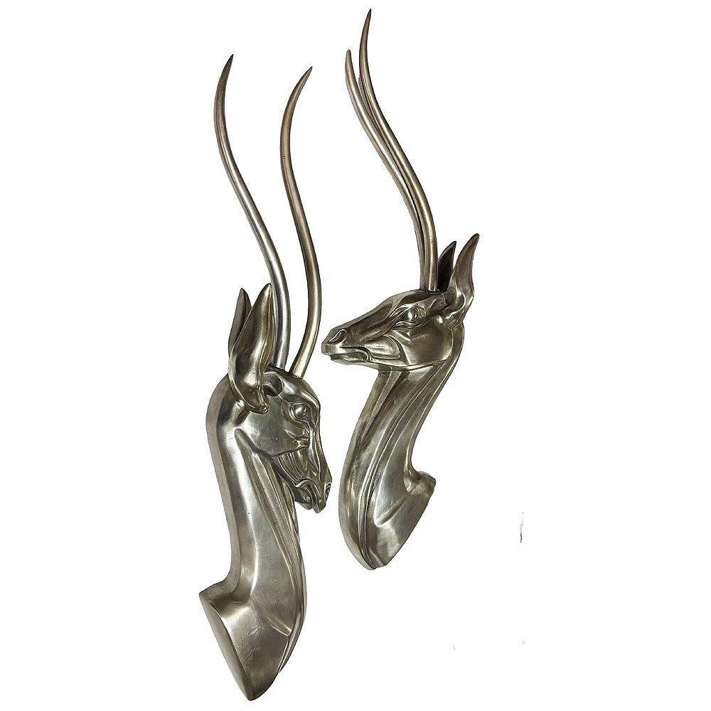 Sculture da parete in alluminio lucido altamente dettagliate con due profili di busti di gazzella. Le loro forme eleganti e stilizzate catturano l'essenza aggraziata delle gazzelle con linee pulite e una lucentezza metallica. Le sculture evocano il