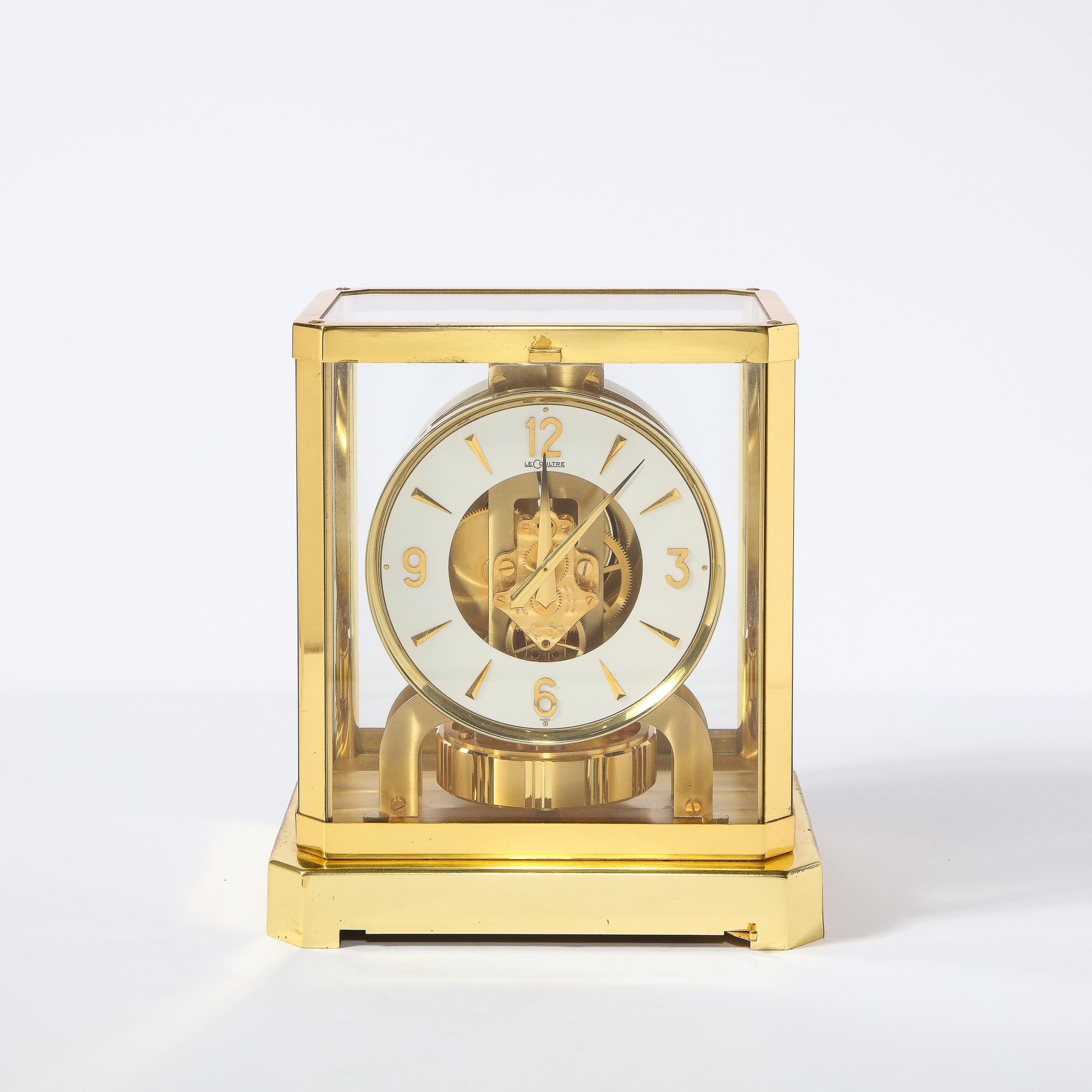 This stunning modernist desk clock was realized by the fabled Swiss watch maker Jaeger Le-Coultre. It features a polished brass open frame body with translucent glass walls that surround the clock. The clock features a white dial with markers and