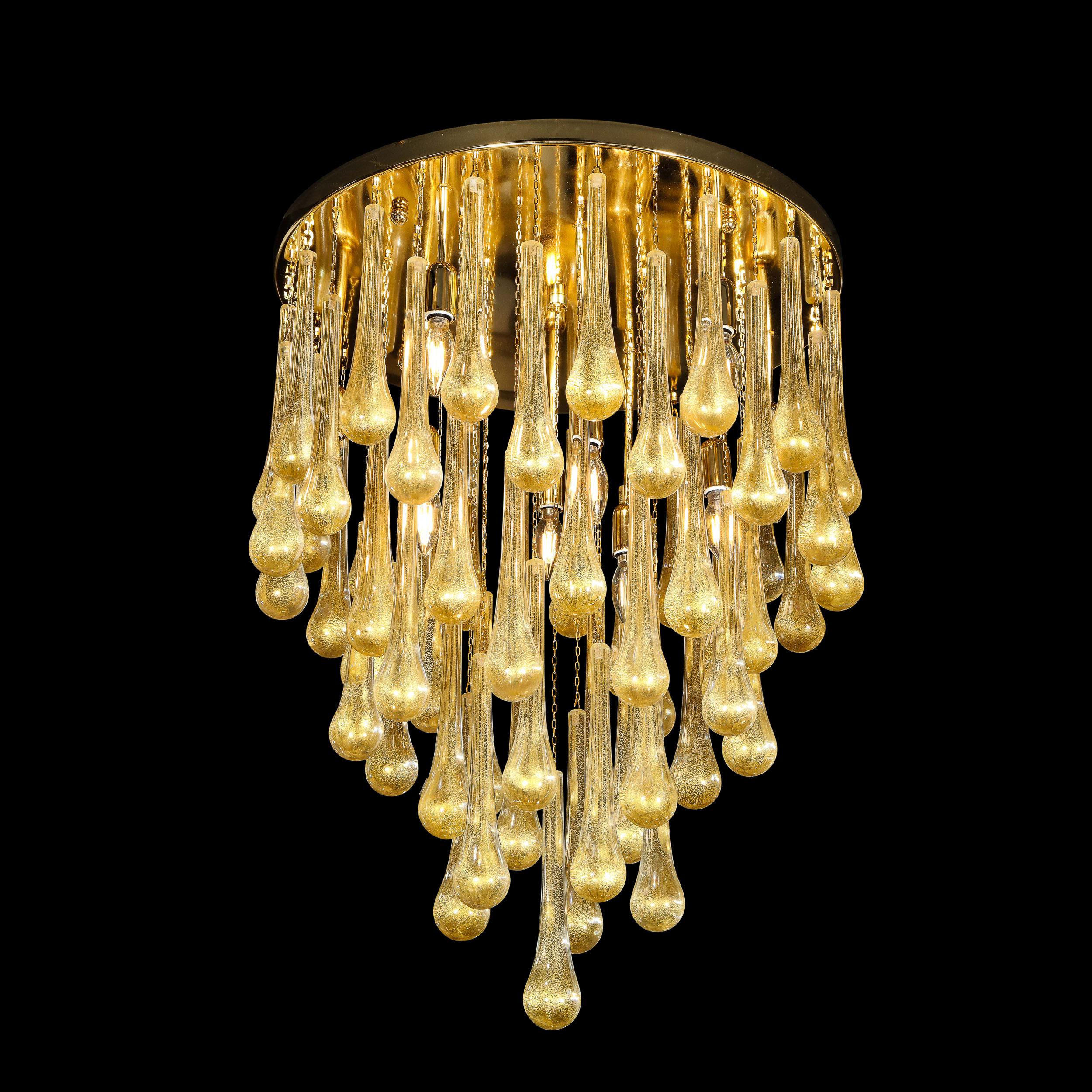 This stunning modernist teardrop flush mount chandelier was hand blown in Murano Italy- the island off the coast of Venice renowned for centuries for its superlative glass production. It features a circular polished brass canopy with a wealth of