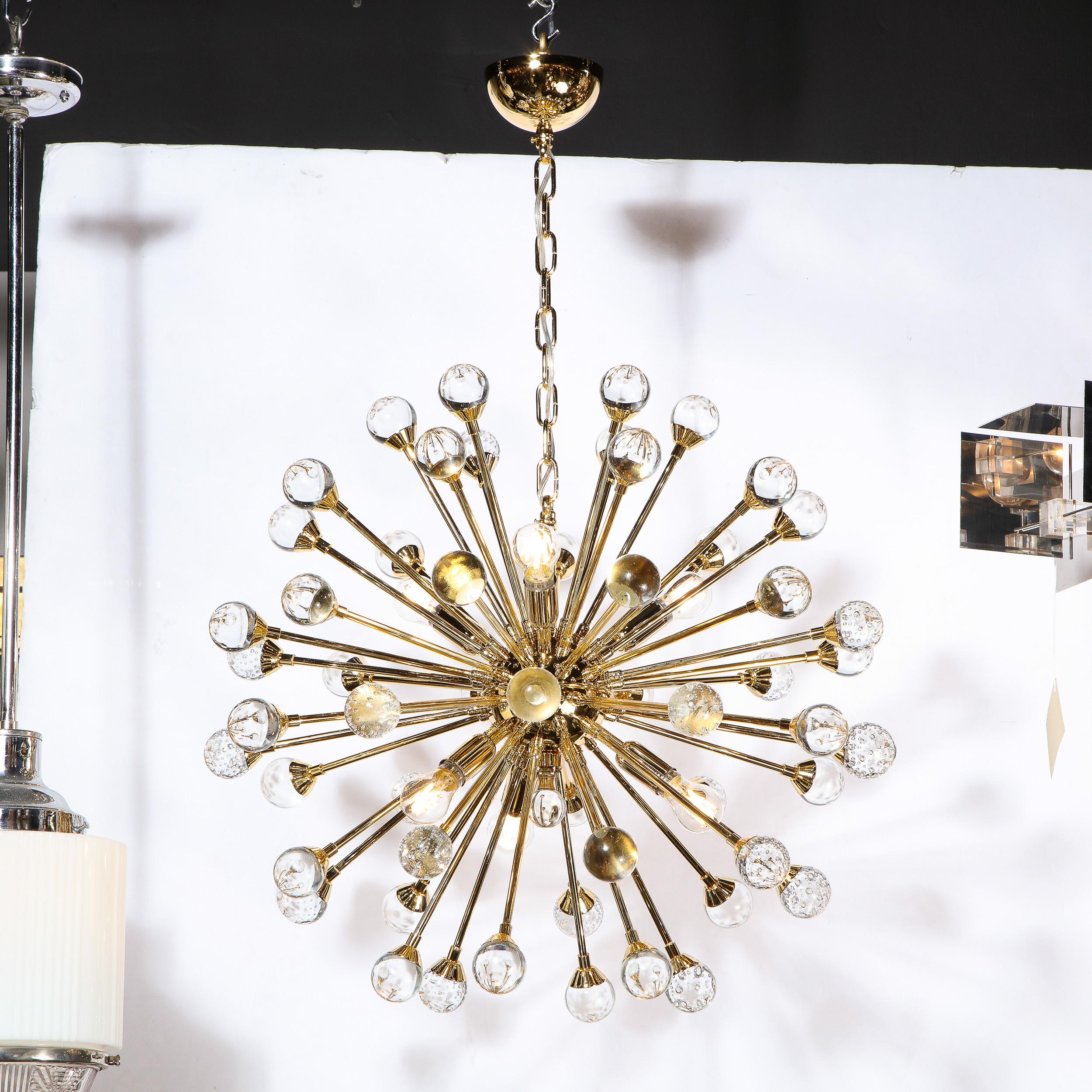This stunning and graphic modernist sputnik chandelier was realized in Murano, Italy- the island off the coast of Venice renowned for centuries for its superlative glass production. It features a spherical body in lustrous polished brass with an