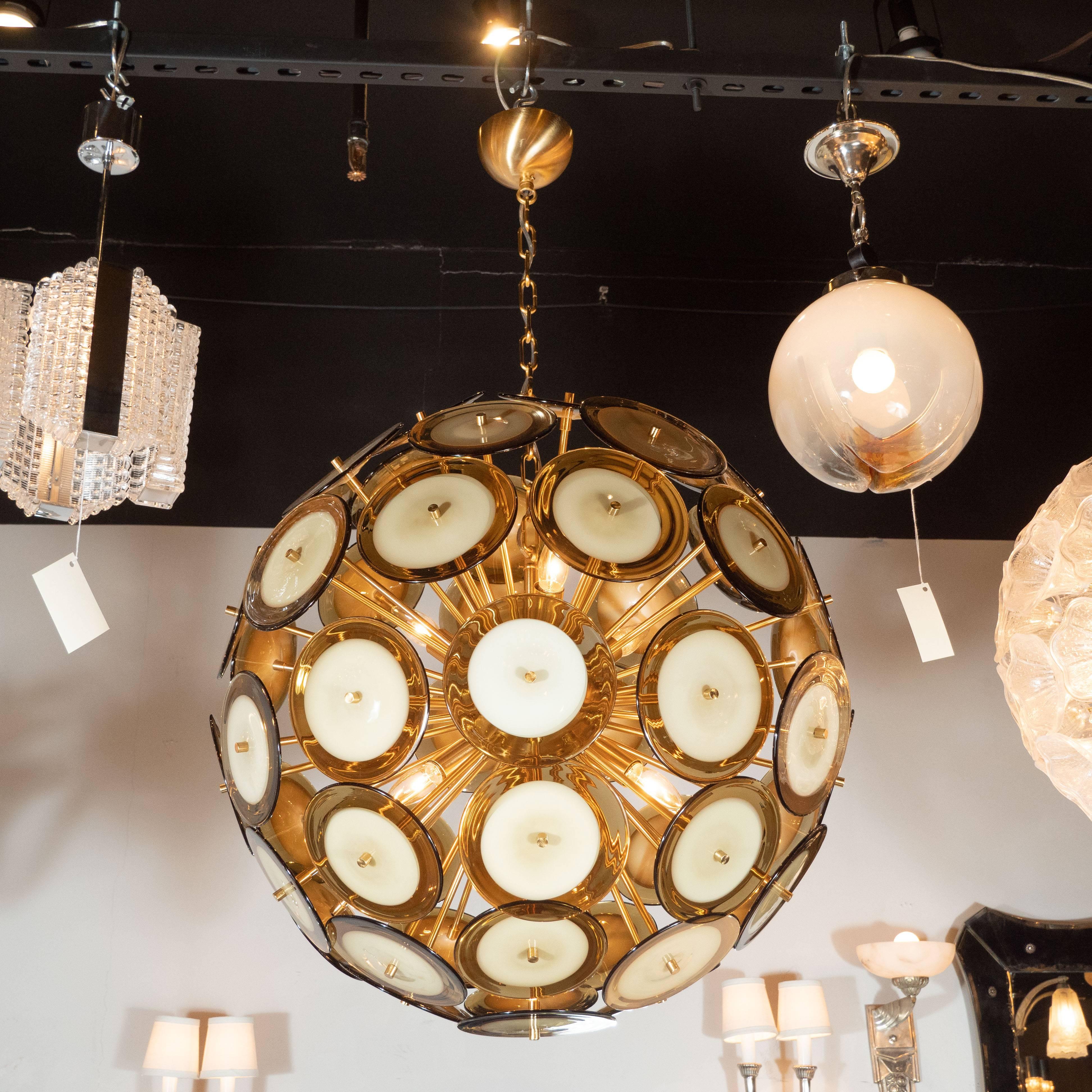 This sophisticated and stunning chandelier was realized in Murano, Italy- the islands off the coast of Venice renowned for centuries for their superlative glass production. It features an abundance of polished brass rods emanating from a central orb
