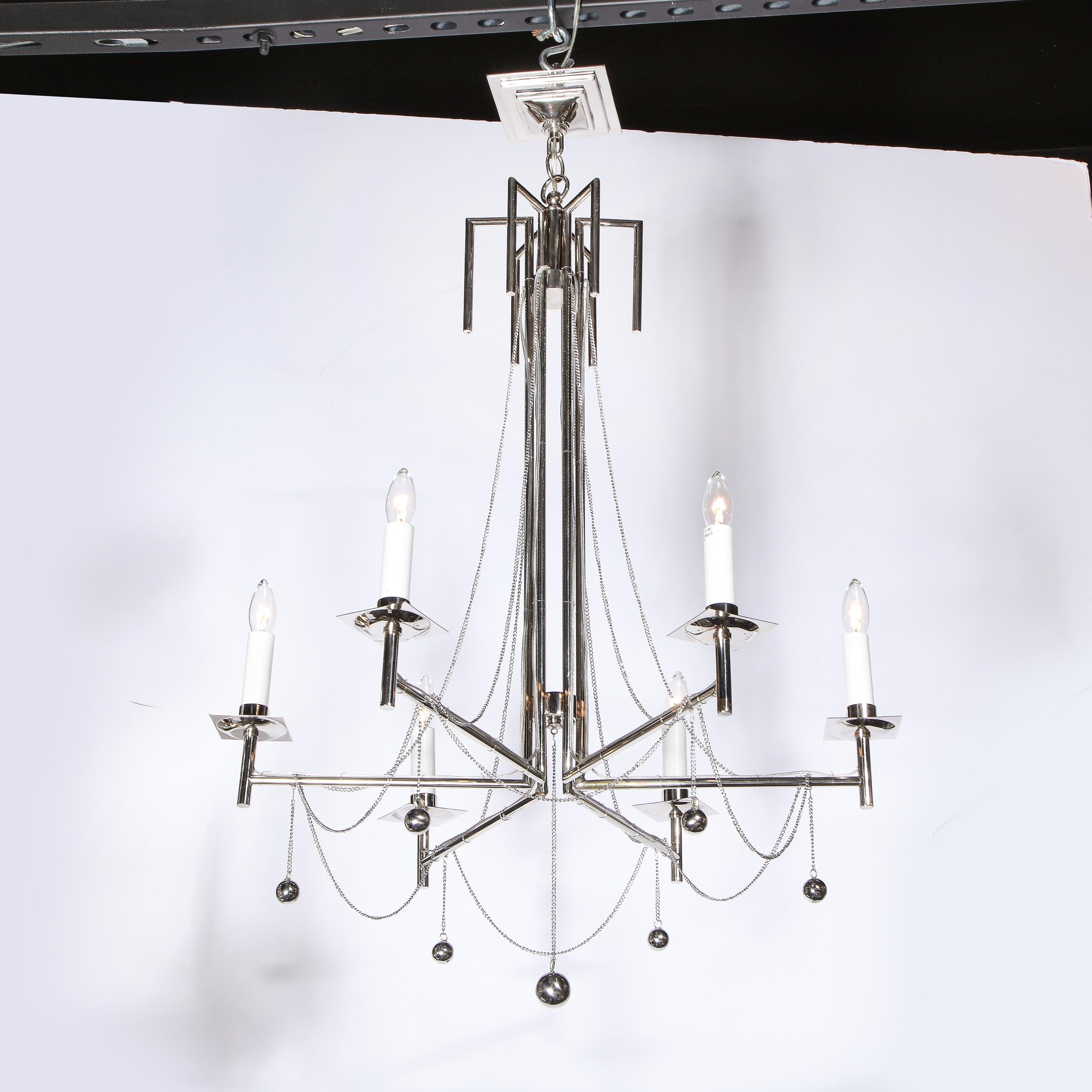 This stunning modernist six arm polished nickel chandelier was realized in the United States in the latter half of the 20th century. It offers six cylindrical polished chrome arms that extend outwards at right angles from vertical rods (of the same