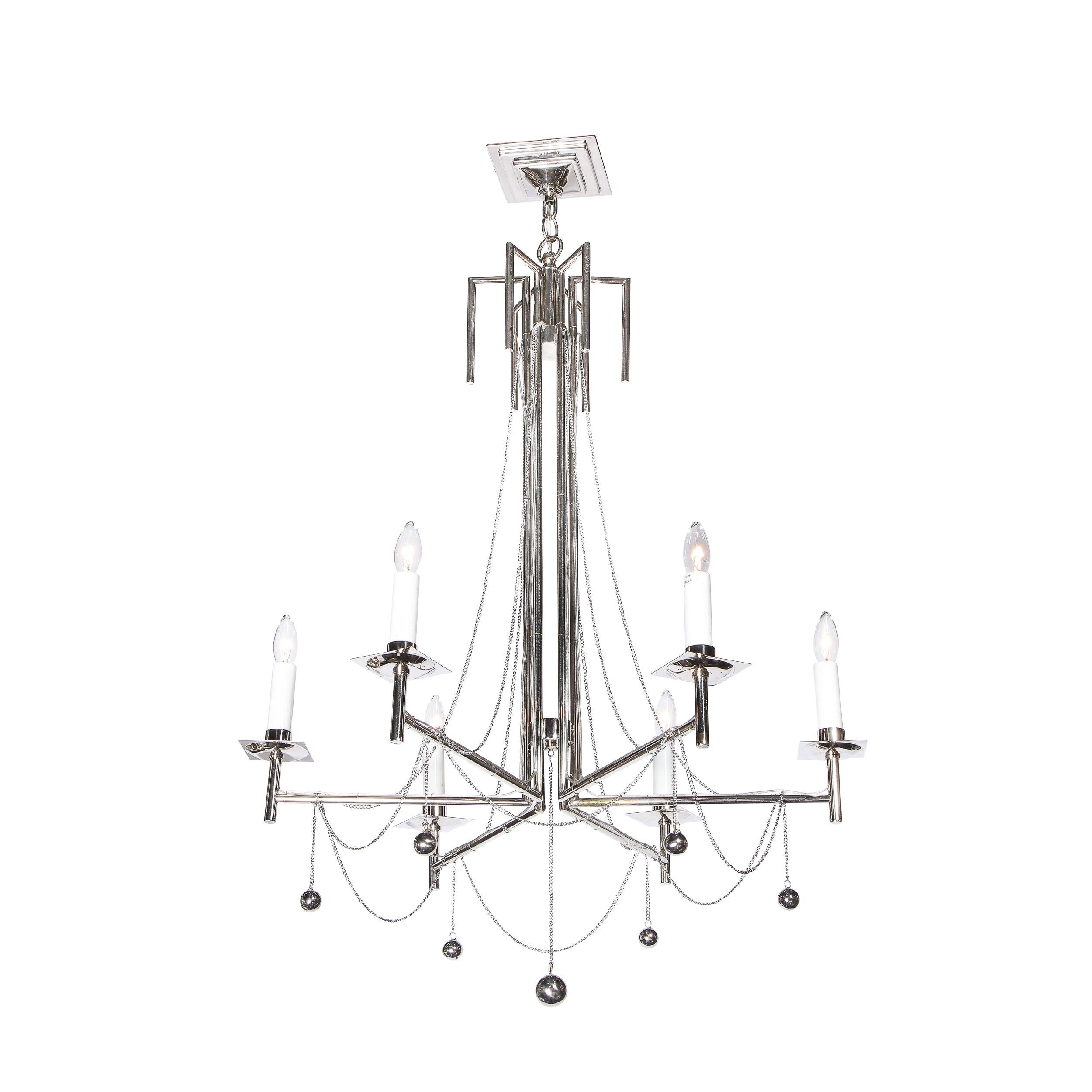 This stunning modernist six arm polished nickel chandelier was realized in the United States in the latter half of the 20th century. It offers six cylindrical polished chrome arms that extend outwards at right angles from vertical rods (of the same