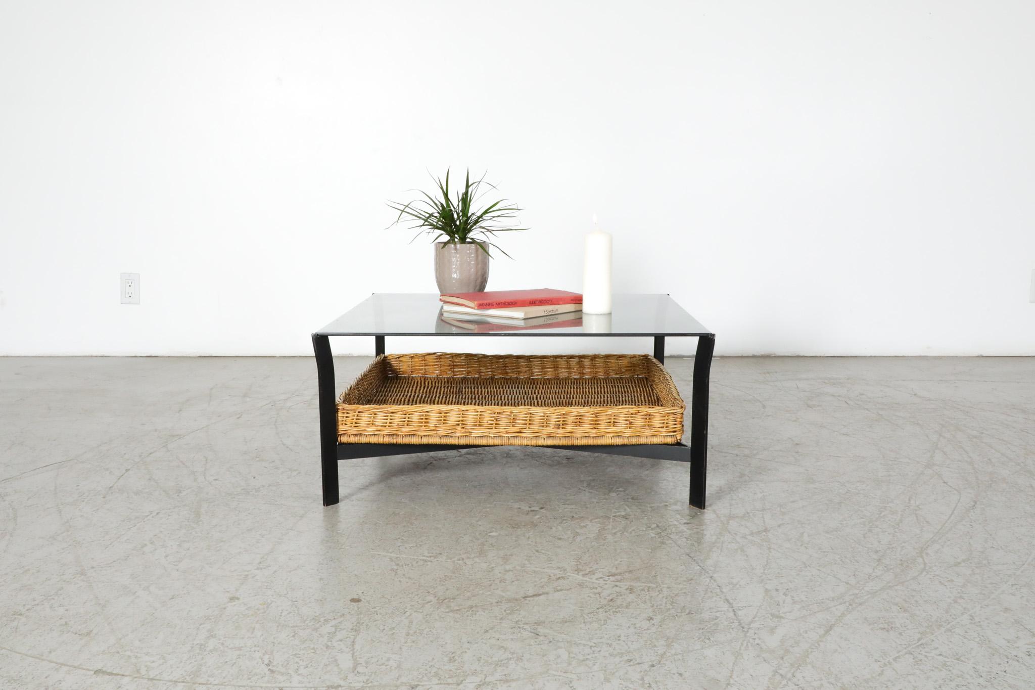 Mid-Century, 1960's, black enameled metal coffee table with lower rattan basket, designed by Dutch post-war design great Rudolf Wolff for Rohe Noordwolde. A handsomely designed square metal frame paired with a dark smoked glass top and woven rattan