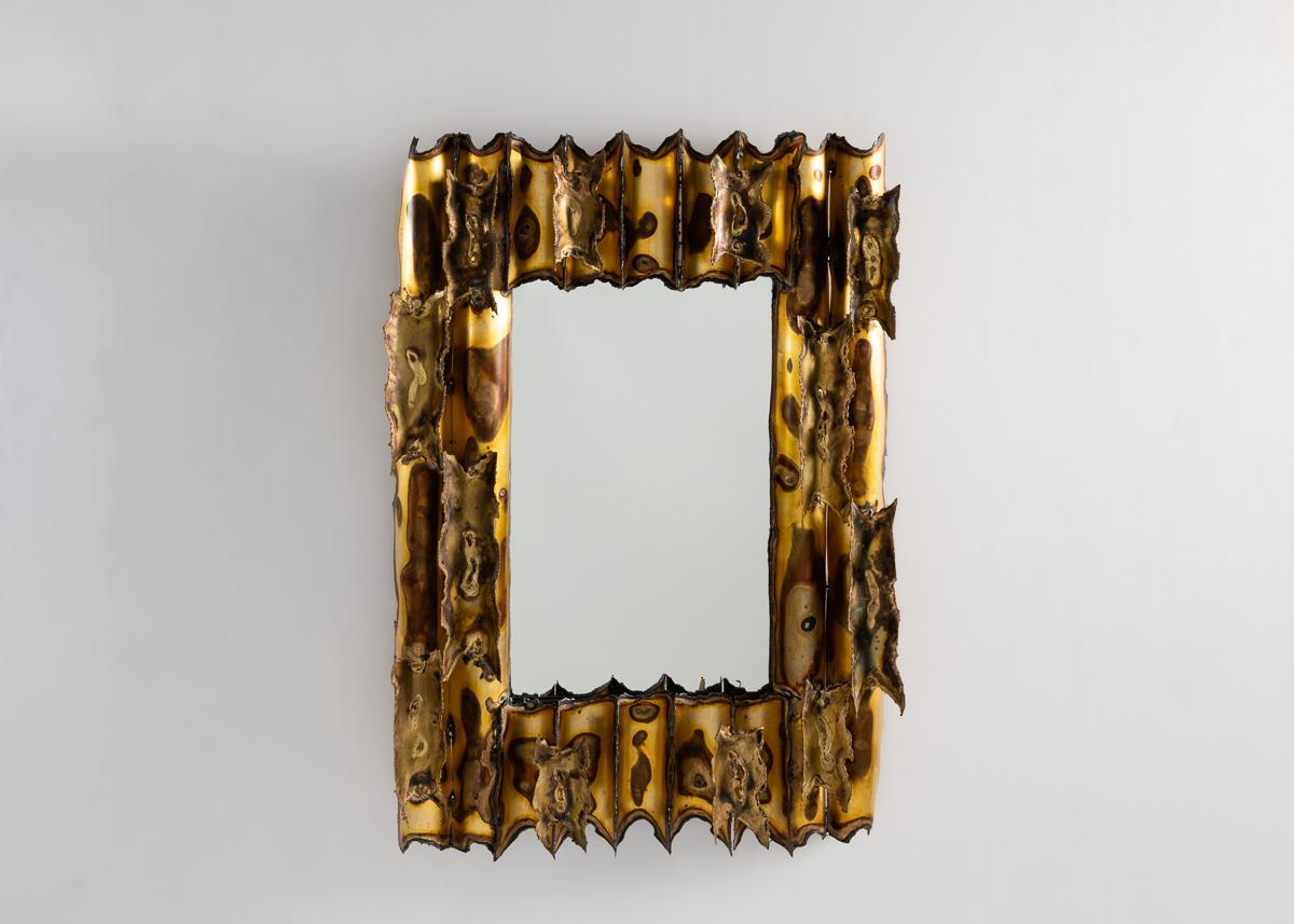 Ce remarquable miroir a un cadre composé d'un intriguant motif de cylindres de laiton biseautés, oxydés diversement pour créer un bel effet presque naturel qui oppose l'ordre au désordre, la création à la désintégration.