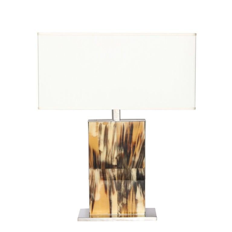 This sophisticated pair of modernist paneled Horn and polished nickel table lamps were realized in the United States during the latter half of the 20th century. they feature a rectangular polished nickel base that extends beyond the perimeter of the