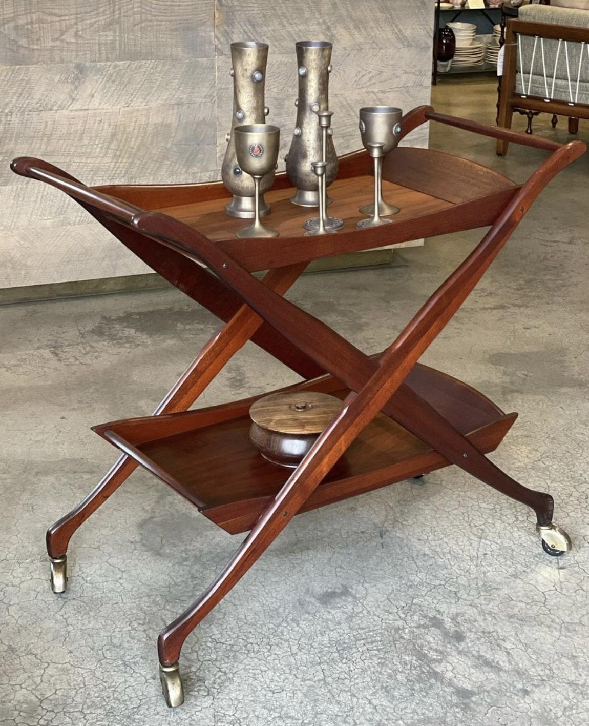 YOUR DRINK IS SERVED! 🍸

Serve your cocktails off this handsome Modernist rolling Walnut bar/tea cart with its striking 'X' frame design. It has two trays with raised edges, sexy sleek legs and brass casters.

It measures 37