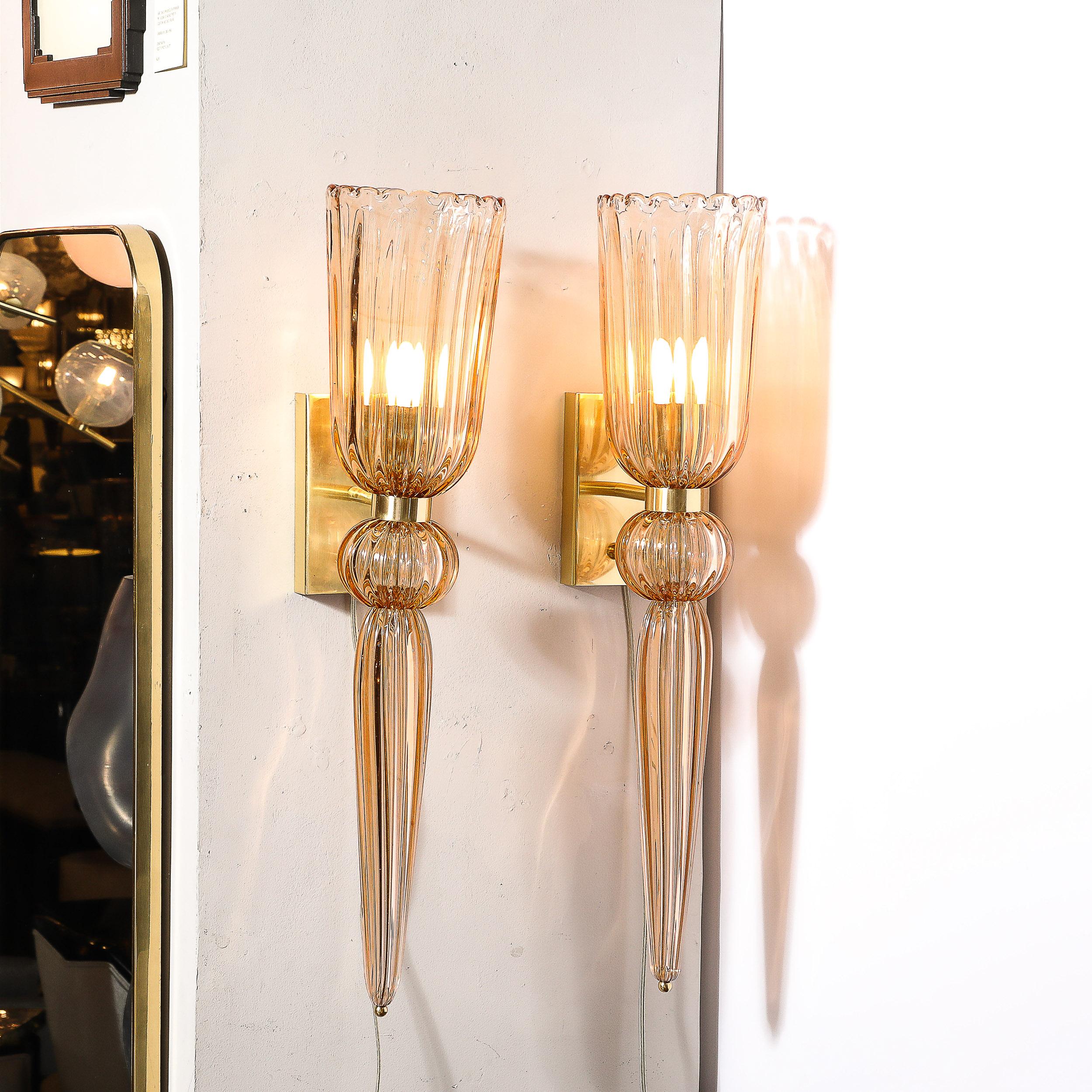 This gleaming and elegant Pair of Modernist Smoked Rose Hand-Blown Murano Glass & Brass Sconces W/ Elongated Drop originates from Italy during the 21st Century. Featuring a beautiful elongated form with fluted detailing across the variety of glass