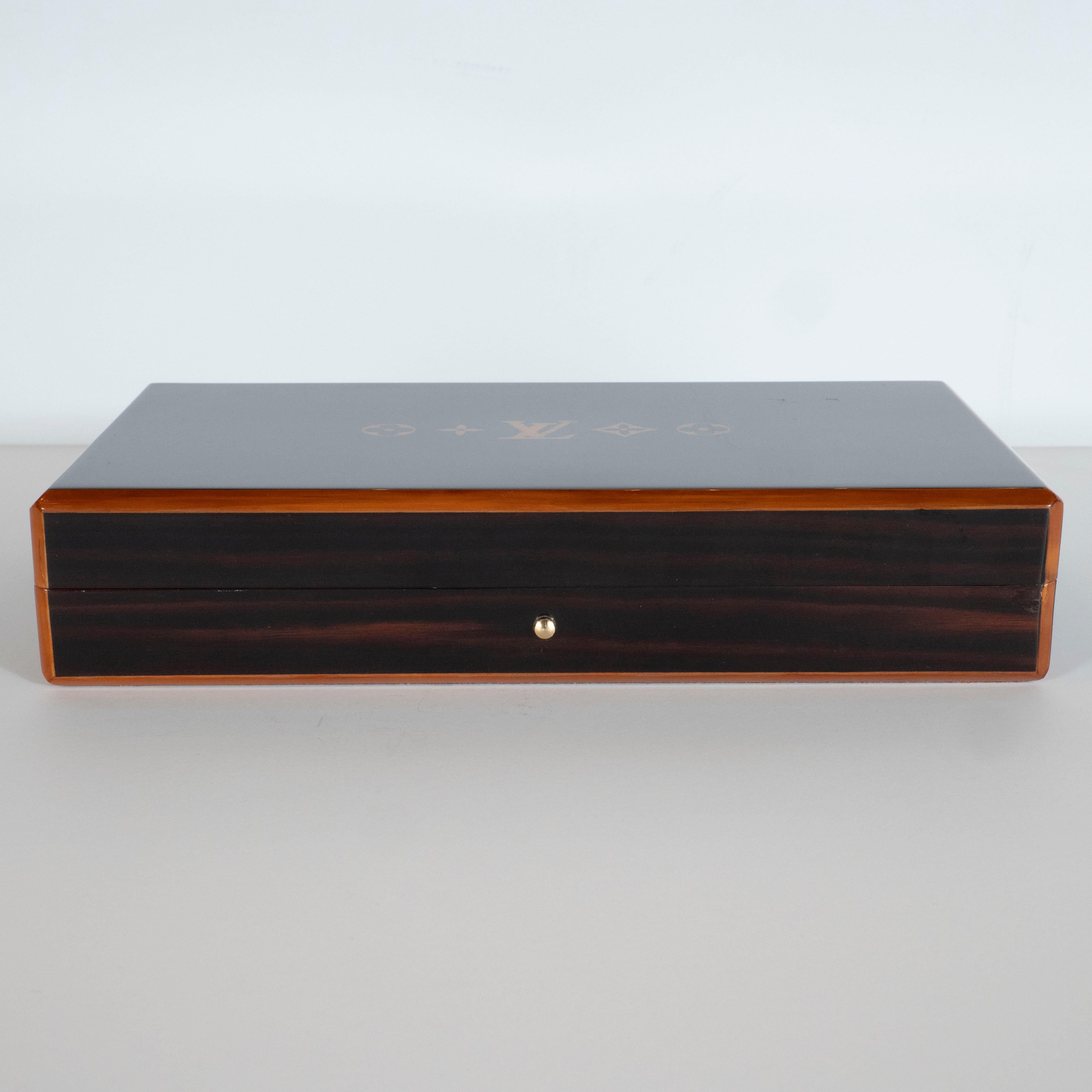 This elegant humidor was realized by Louis Vuitton- one of the world's premiere luxury brands since its inception in 1854. Executed in lacquered dark rosewood with blonde holly trim around the exterior, the humidor offers a volumetric rectangular