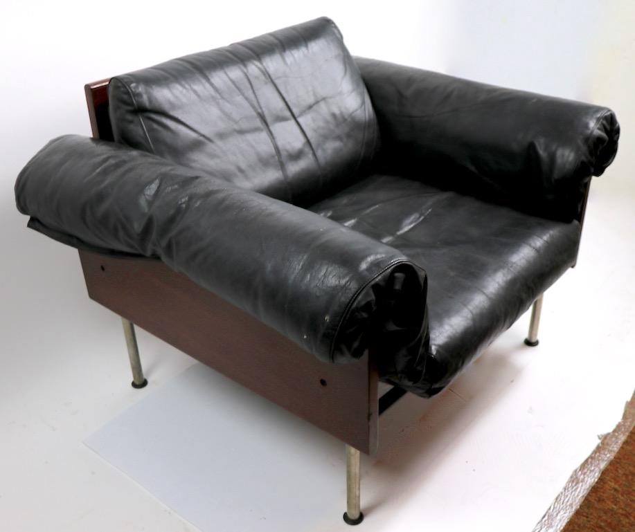 Very stylish and chic low lounge chair with solid rosewood sides, and back, supporting top grade down filled leather cushions. The tubular blacken finish steel structure rests on chrome finish tubular legs terminating in black plastic disk form feet