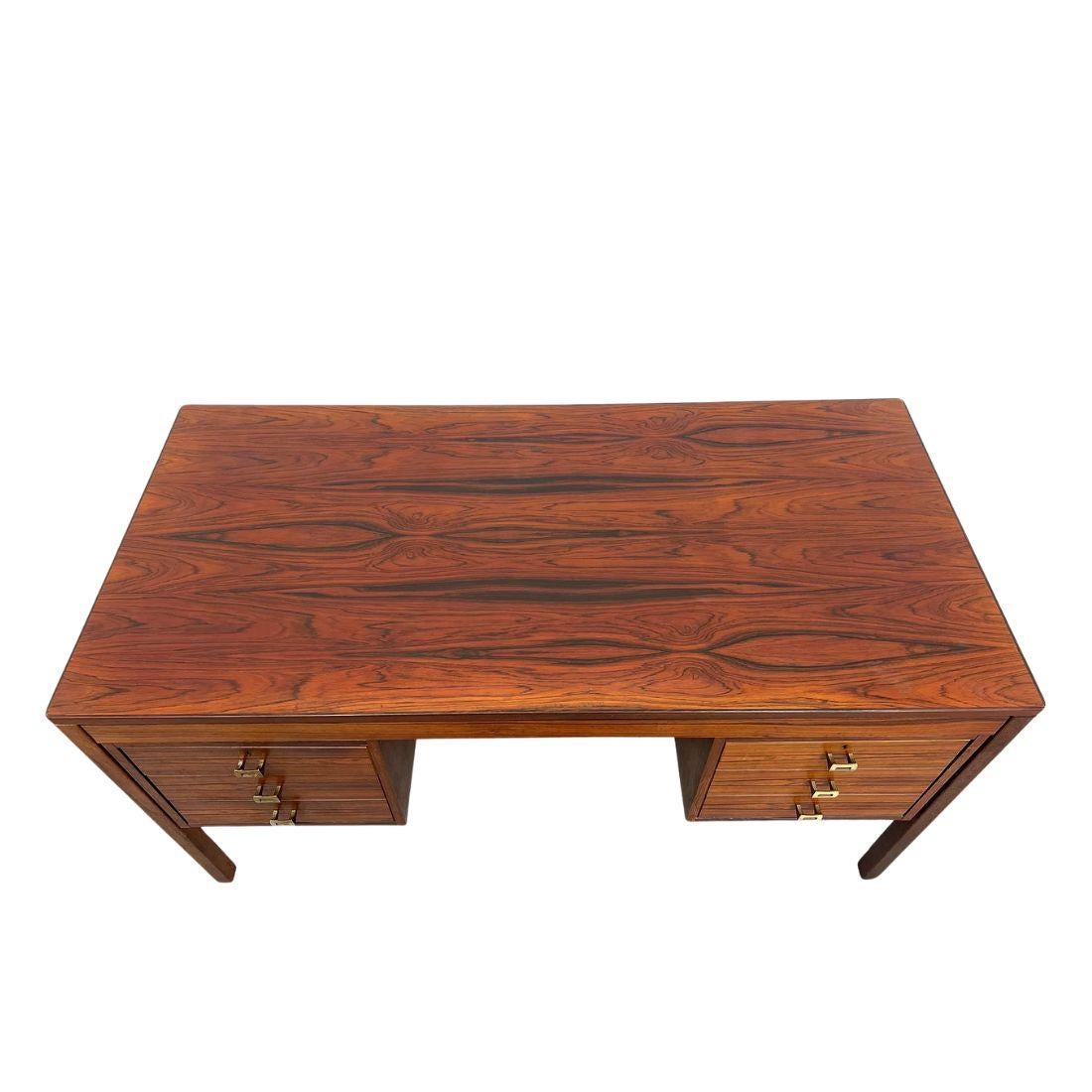 Una scrivania direzionale in stile modernista in palissandro con quattro cassetti.  Bellissima scrivania in legno con tre cassetti sul lato sinistro e un grande cassetto per l'archiviazione sul lato destro.  I tiranti della ferramenta in ottone sono
