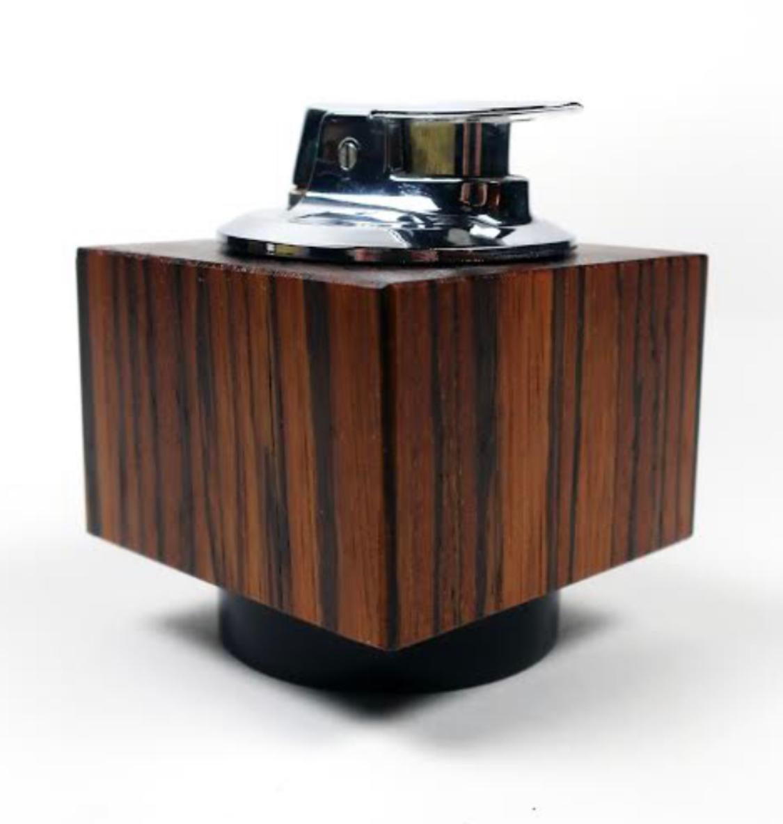 A Brazilian rosewood and chrome cube desktop lighter by Ronson in the epitome of Mid-Century Modern style. Includes all original packaging, documentation, and cleaning brush.

In excellent vintage condition and it works! Marked on base 