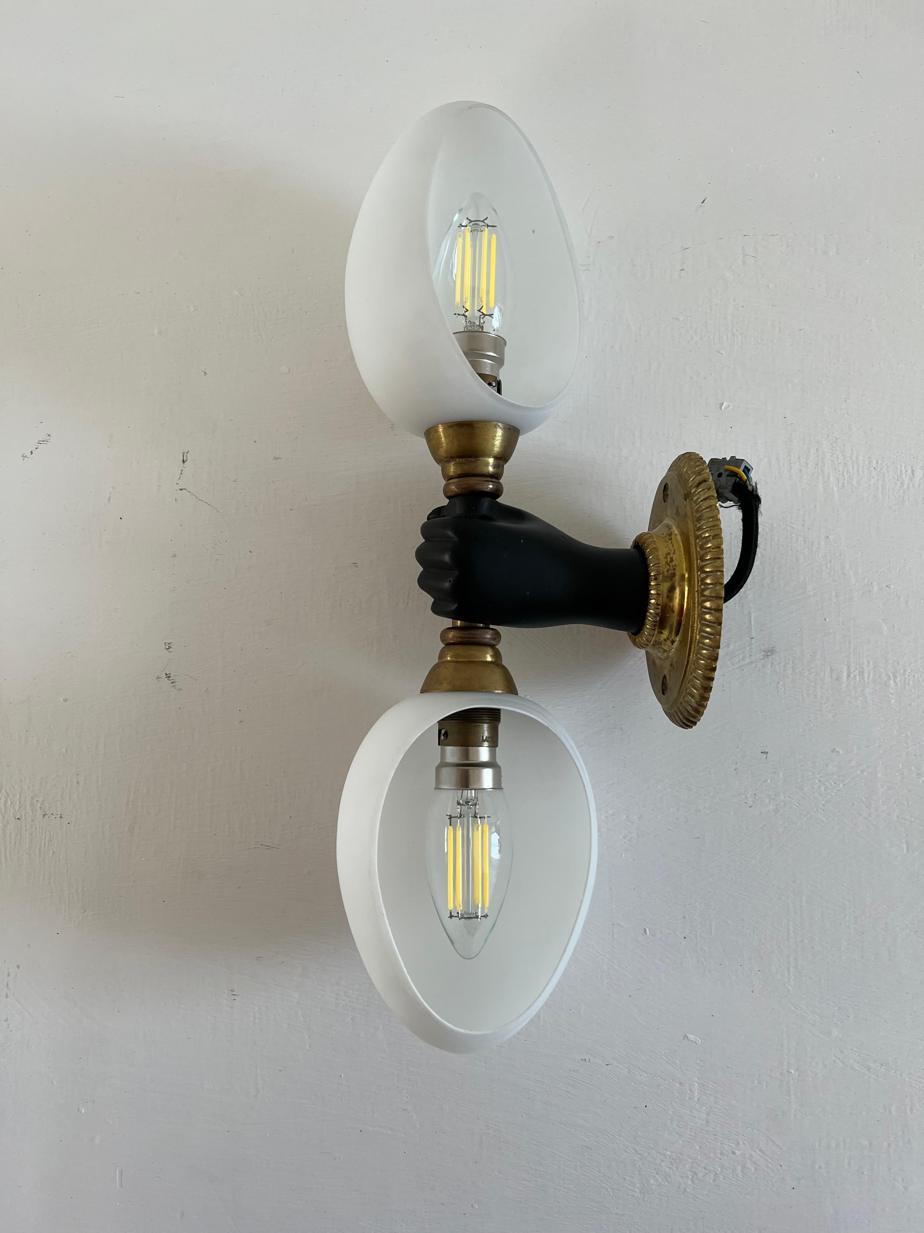 Gorgeous sconce or wall light produced by Maison Arlus in bronze and opaline glass.
Made in France, circa 1950s. 
The light consists of a hand holding 2 positionable half egg opaline shades and takes 2 bayonette bulbs.
There is 1 sconce available.