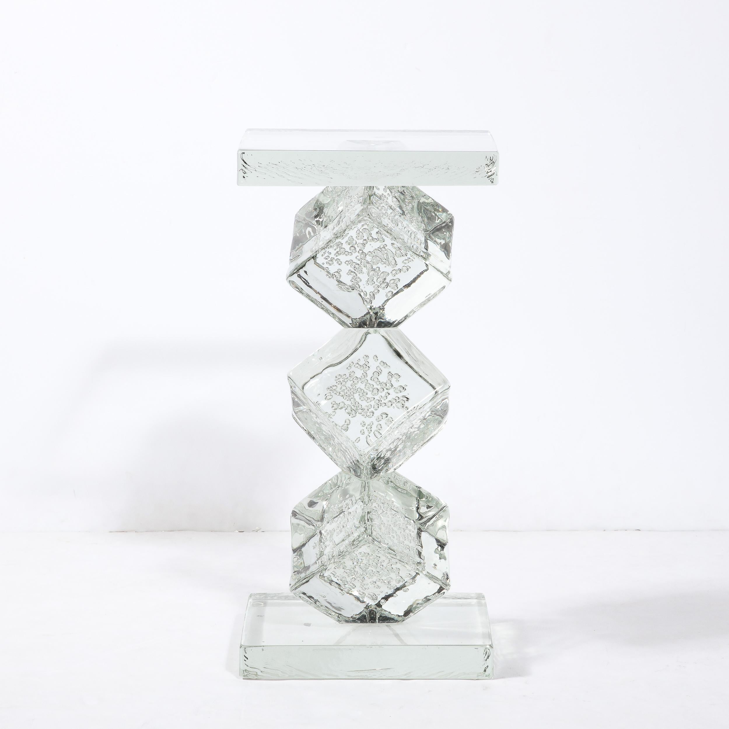 This refined and dynamic side/end table was realized in Murano, Italy- the island off the coast of Venice, renowned for centuries for its superlative glass production. It features a rectangular base and top with three stacked volumetric cubes