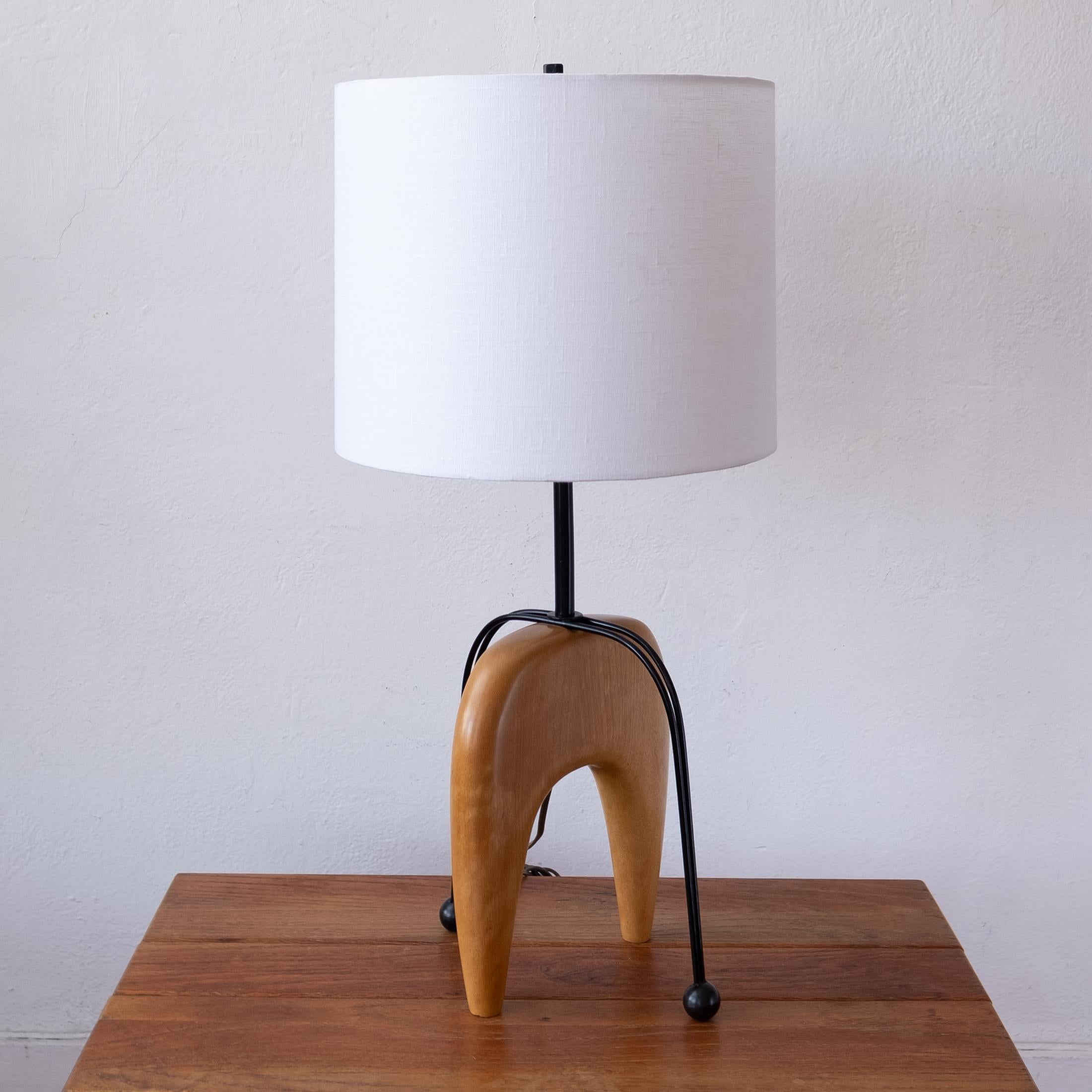 Early 1950s wood and metal table table lamp. Formed sculptural wood base with an arched metal counterbalance. 

Custom linen shade (12