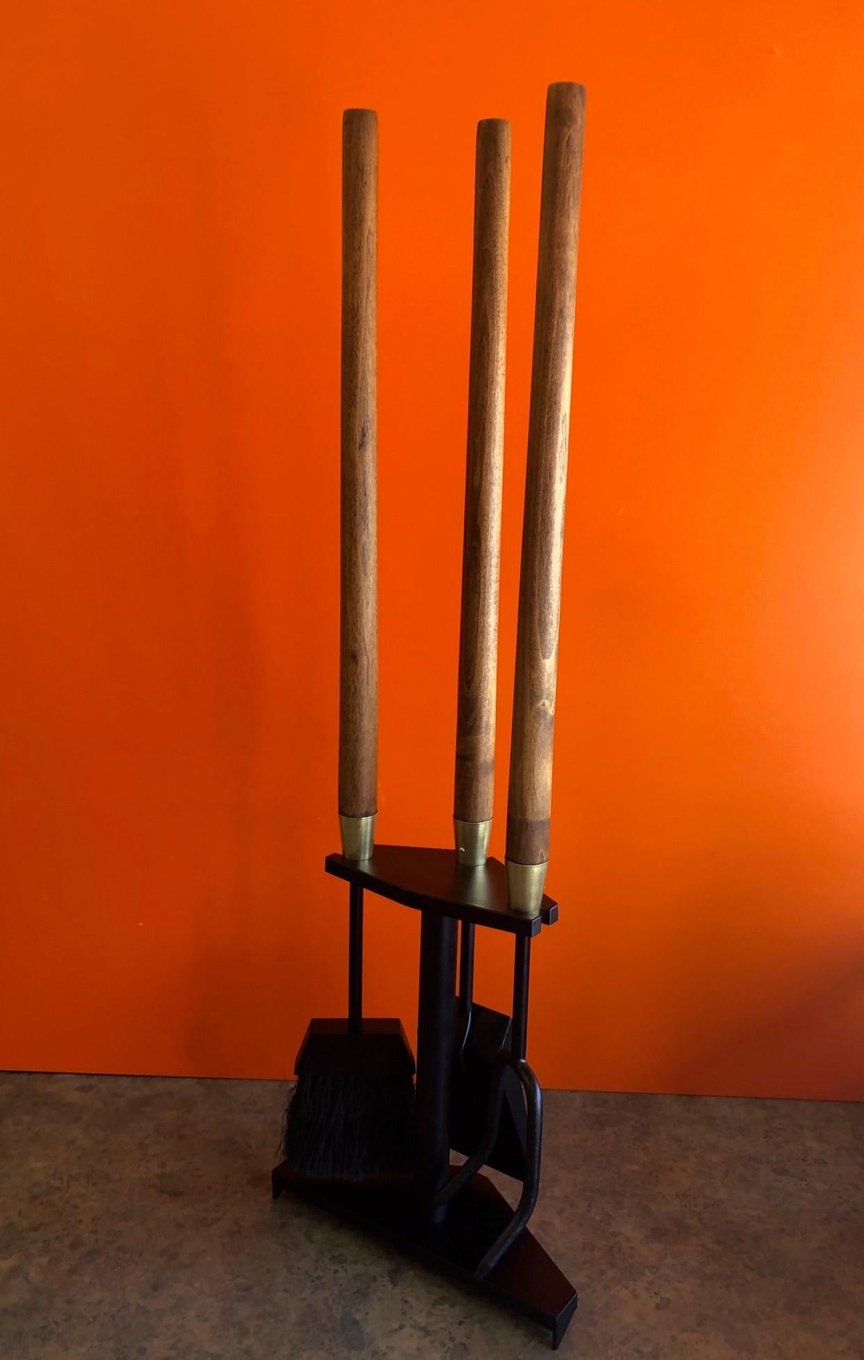 Modernist set of fire place tools in cast iron with brass fittings and walnut handles by Seymour Mfg. of Indiana, circa 1960s. There are three tools (shovel, brush and poker) and a triangular stand in excellent refinished condition. The set measures
