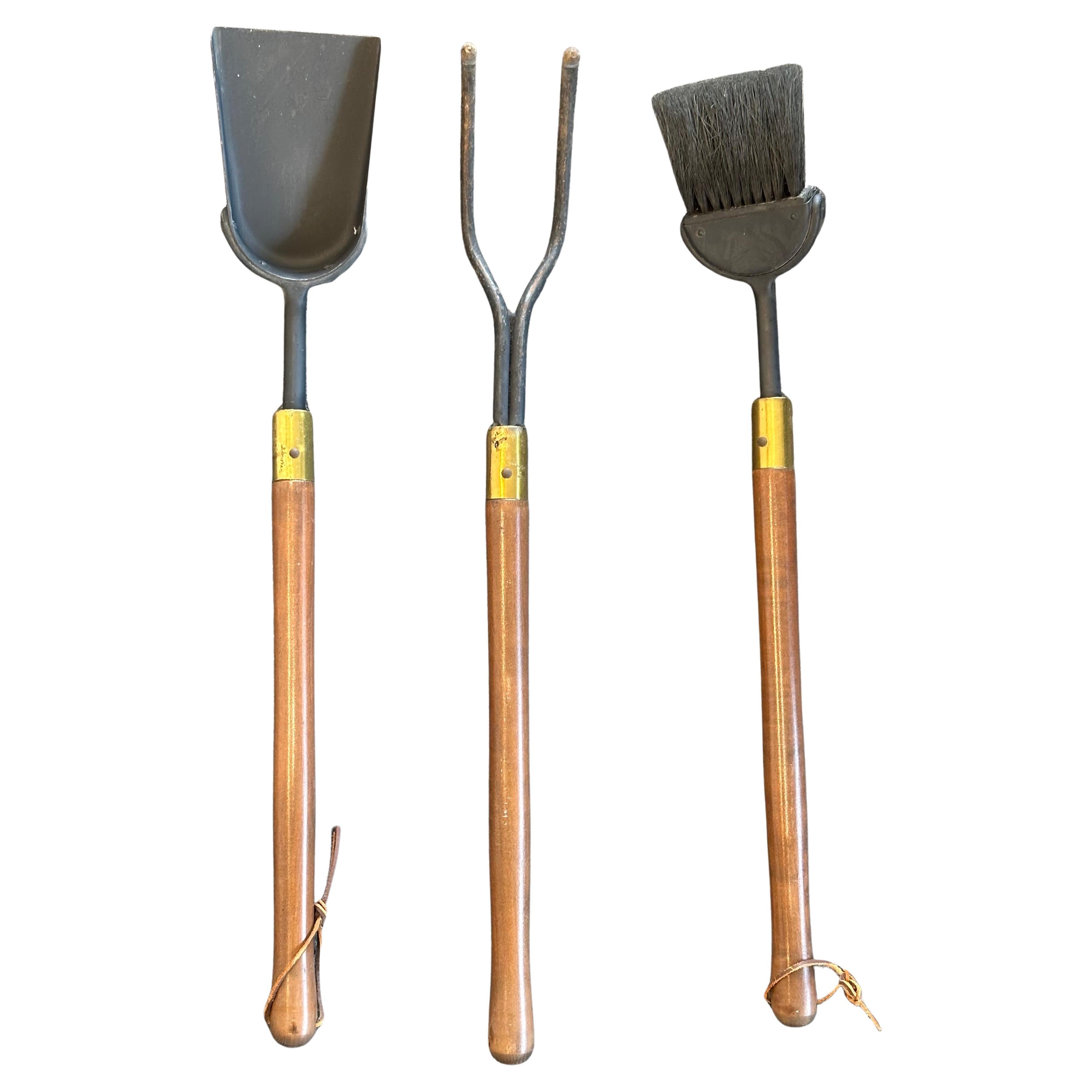 Modernist set of fire place tools in cast iron with brass fittings and walnut handles by Seymour Mfg. of Indiana, circa 1960s. There are three tools (shovel, brush and poker) and a triangular stand in well worn condition with a nice vintage patina.