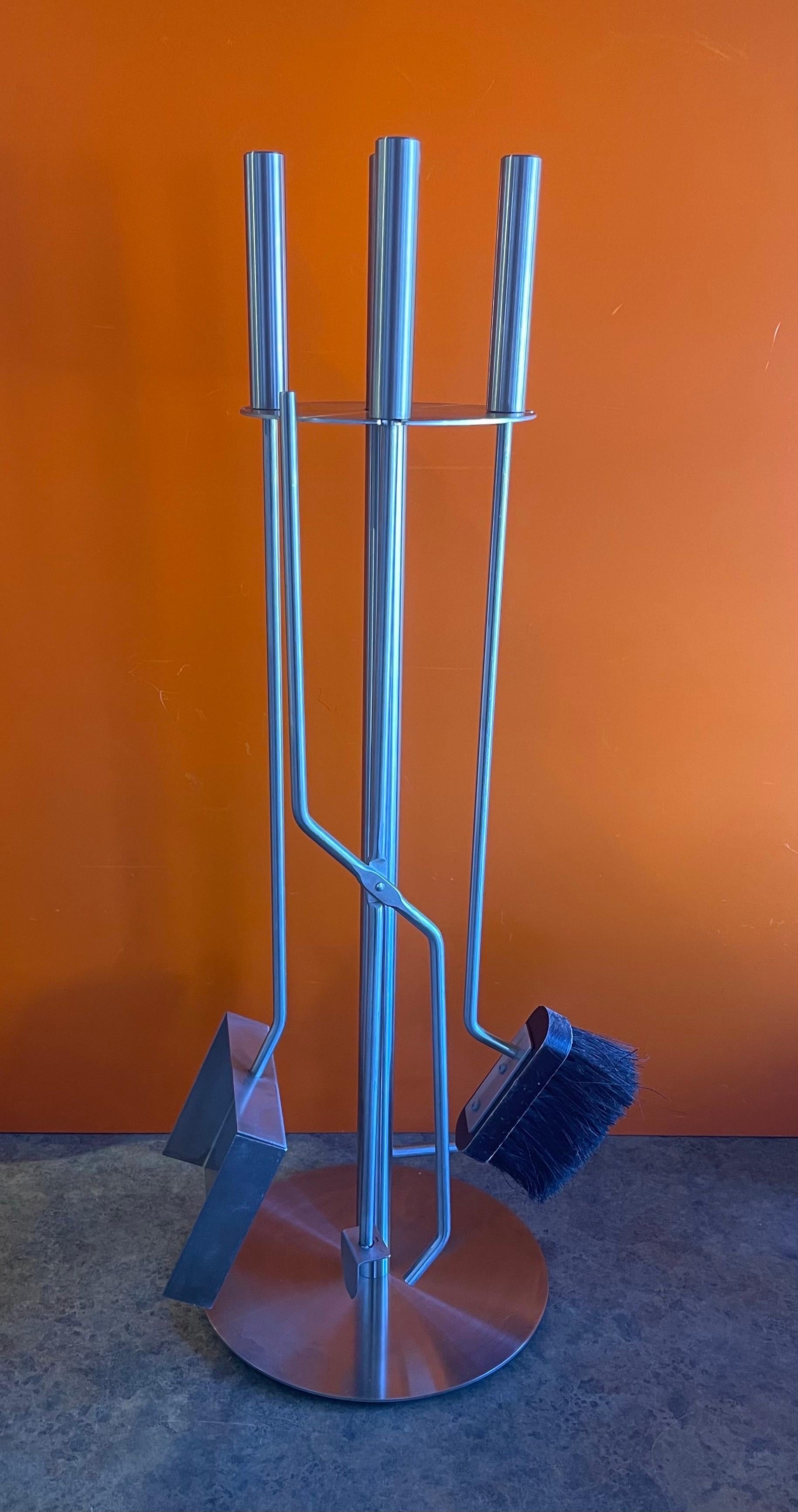 Modernist set of four stainless steel fire place tools, circa 2000s. There are four tools (shovel, brush, log holder and poker) and a single column Stand in very good vintage condition. The set is very heavy and well made; it measures: 31