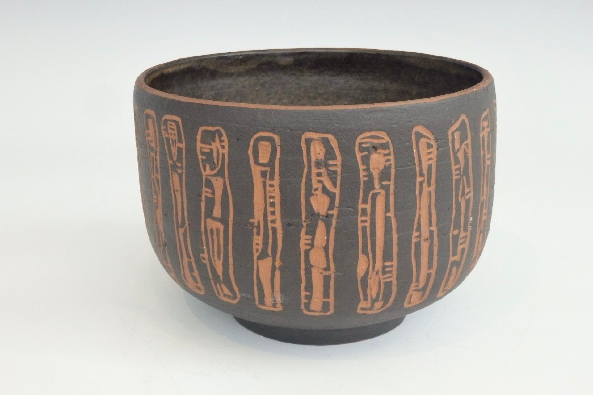 Rozsika Blackstone New York and Arizona, circa 1920-62 pottery vessel.
Deep bowl in dark brown glaze, sgraffito decorated in an abstract vertical design allowing the red ware body to show through, raised on circular foot, incised signature R.B.